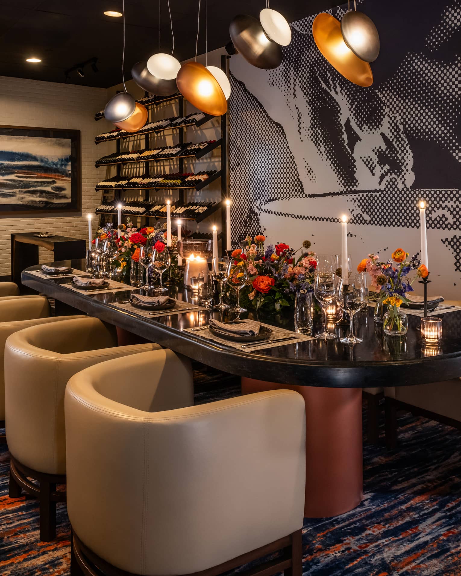 Dining table set with flower vases and candles with lights above and wall art