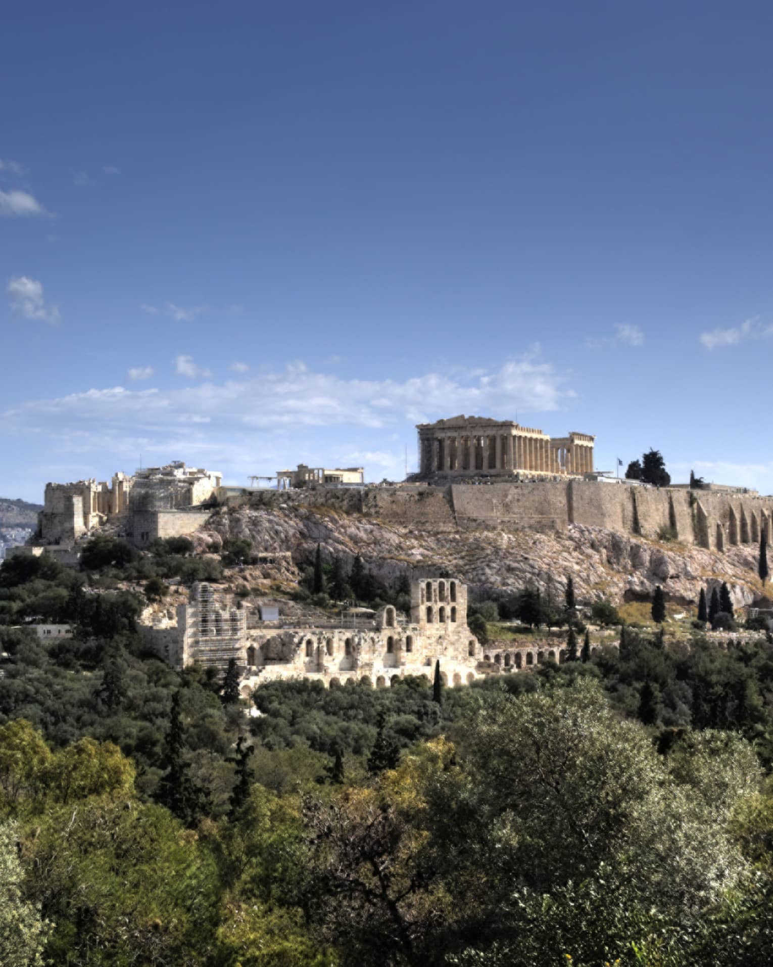 Ancient ruins of Acropolis on mountain surrounded by greenery