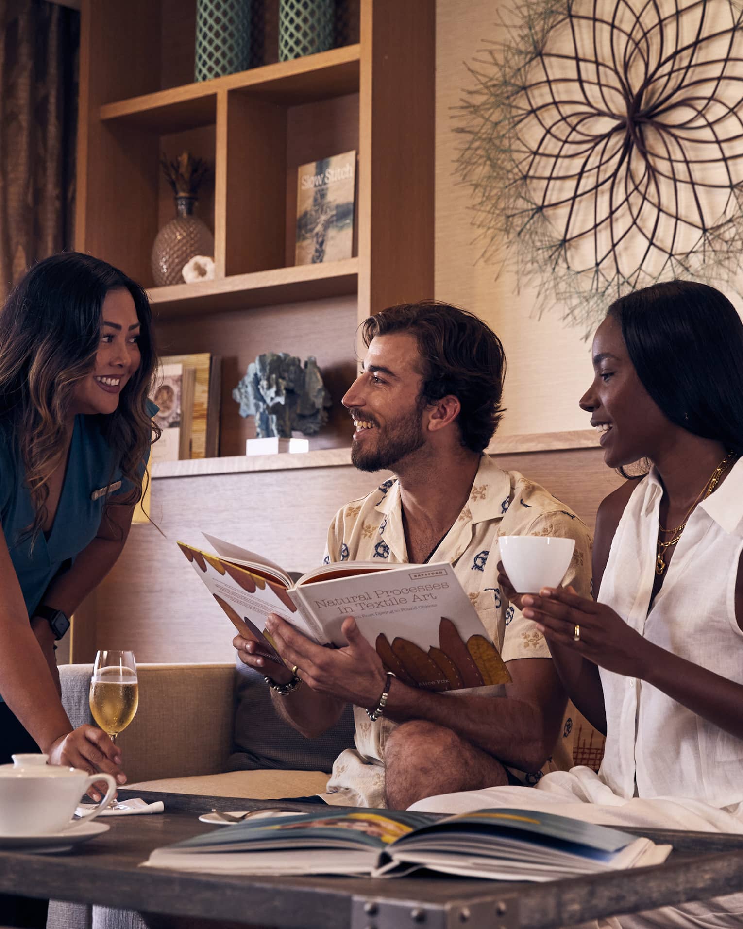Man and woman sit in executive club lounge, served a glass of champagne