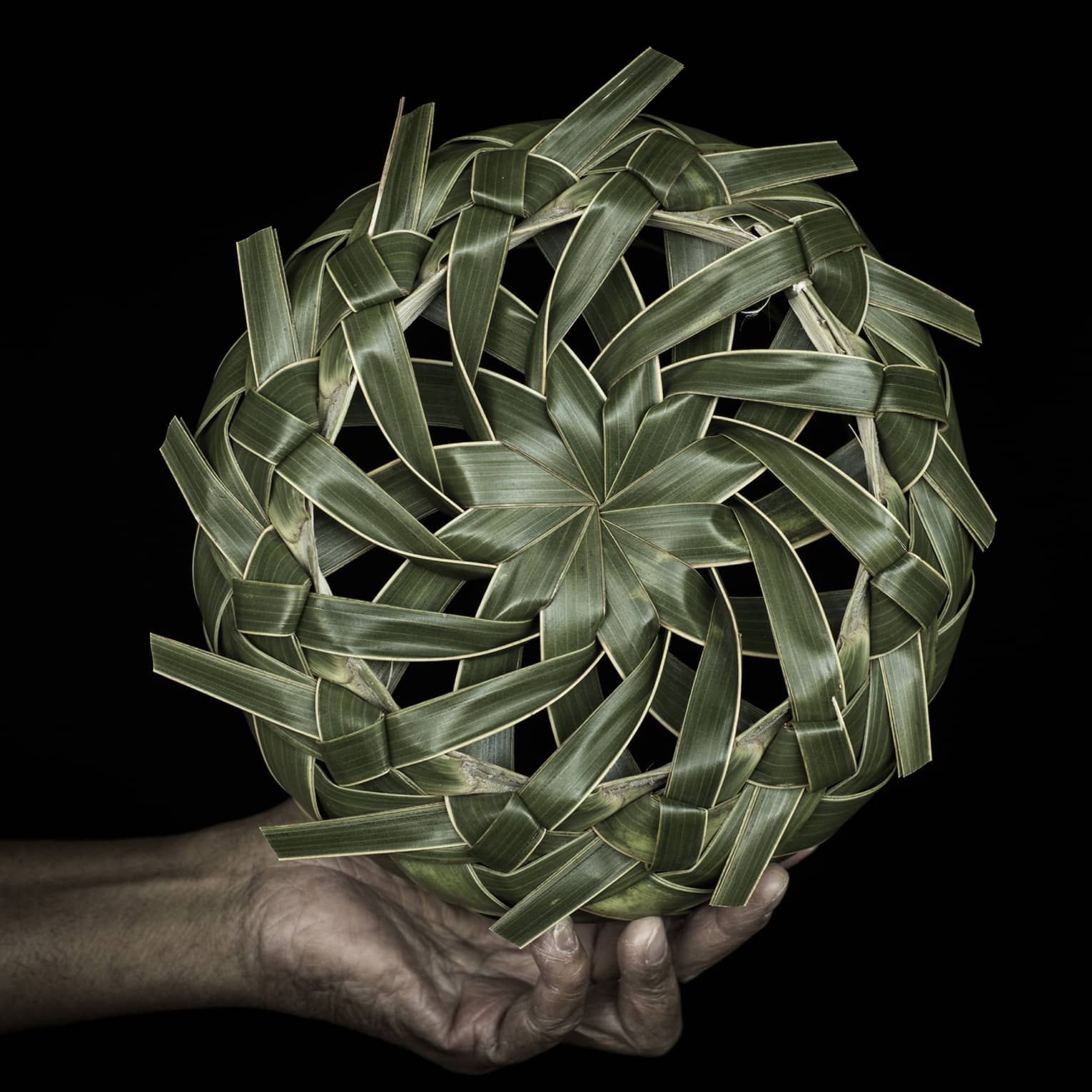 A hand holding a spinning wheel of palm fronds.
