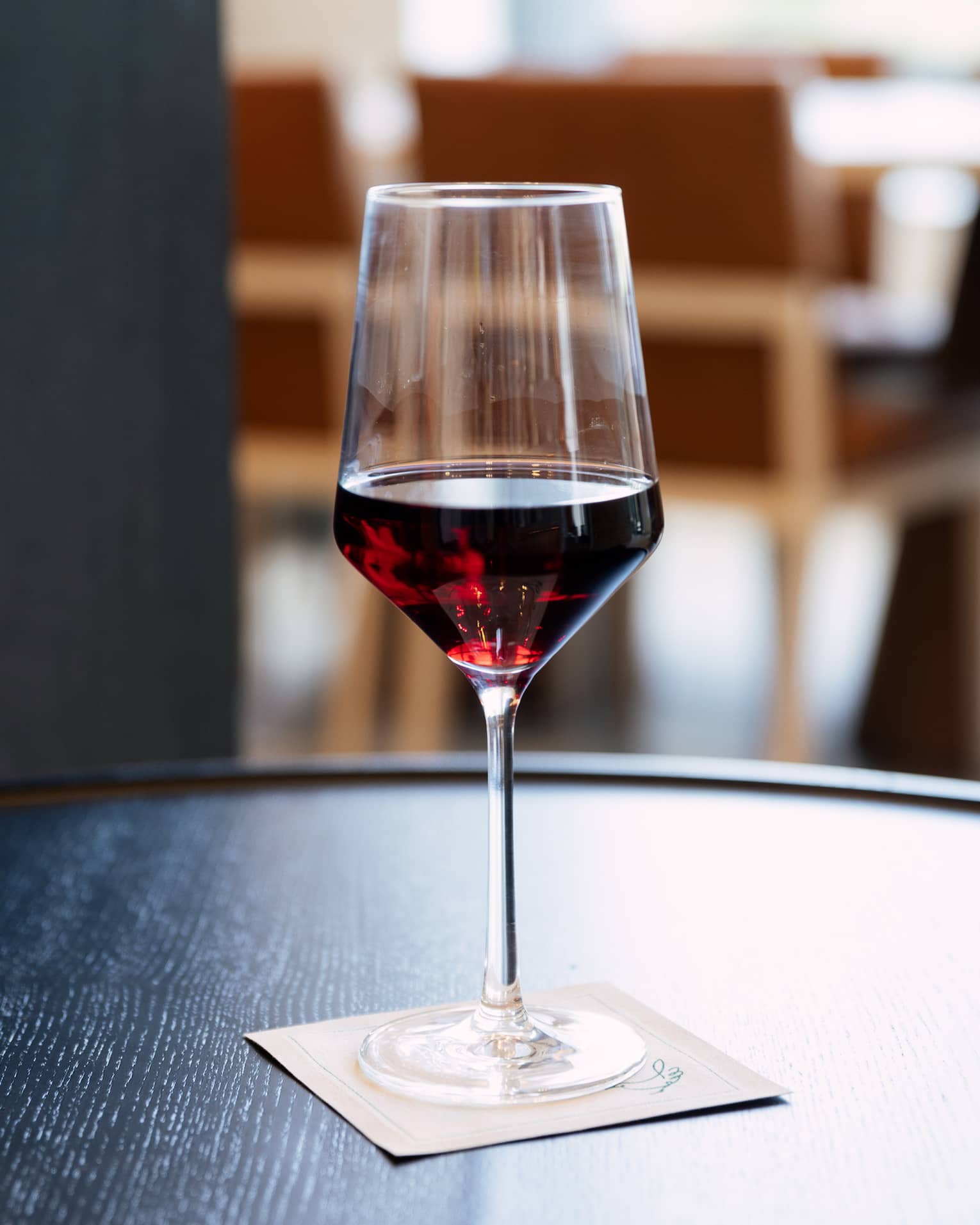 A glass of wine on a round table.