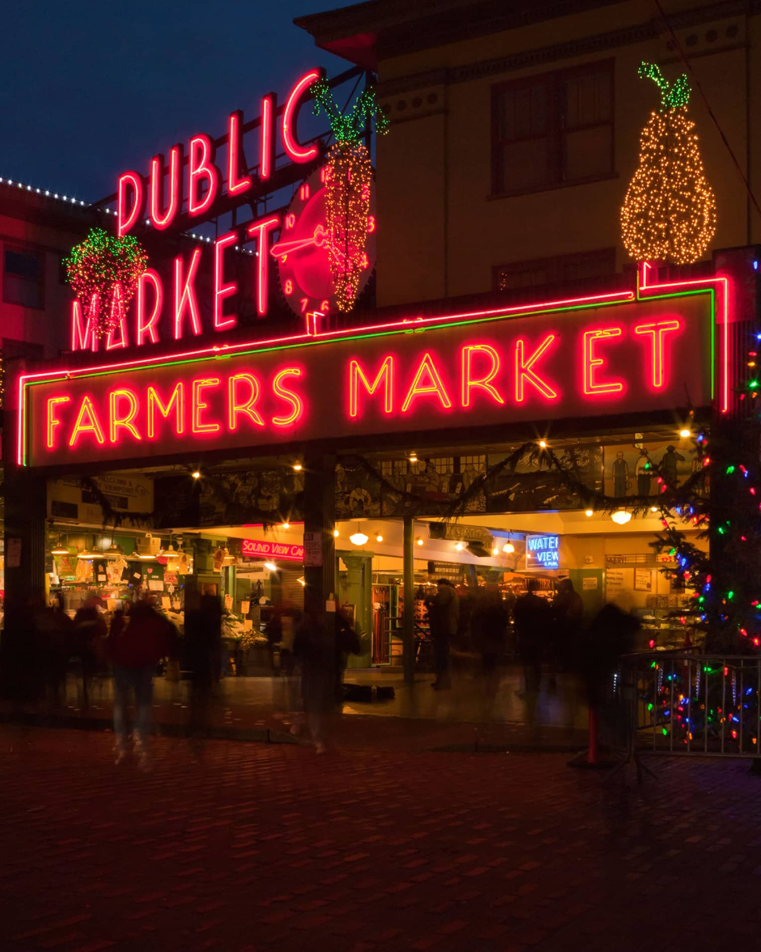 Sign that says "Farmers Market" with a Christmas tree with lights beside it.