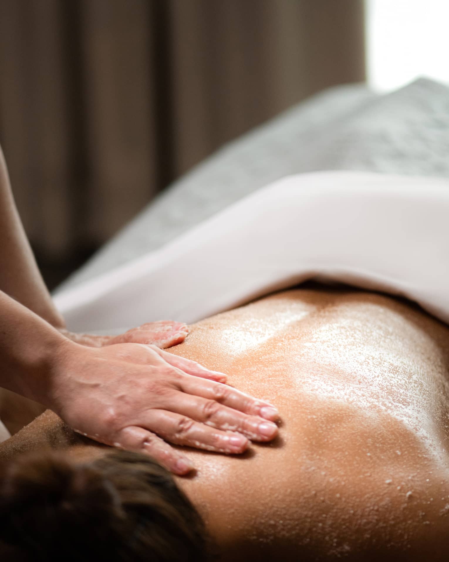 A woman being massaged by a spa staff member while lying down.