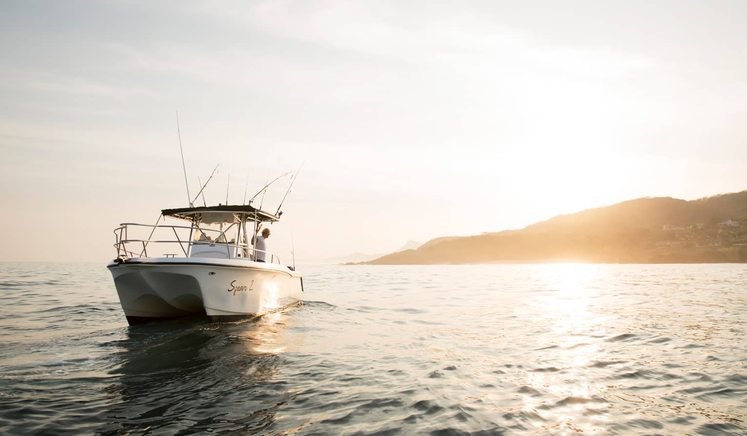 White deep-sea fishing charter fishing boat on water at sunrise 
