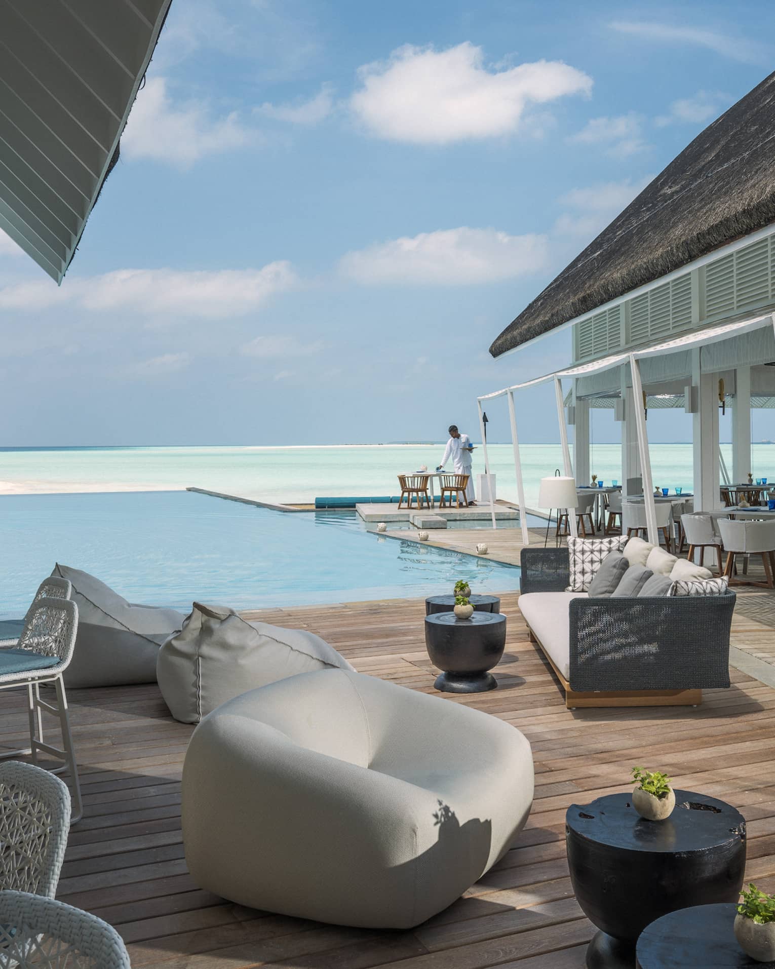 Couches and chairs arranged by a pool overlooking the ocean at the Blu Beach Club