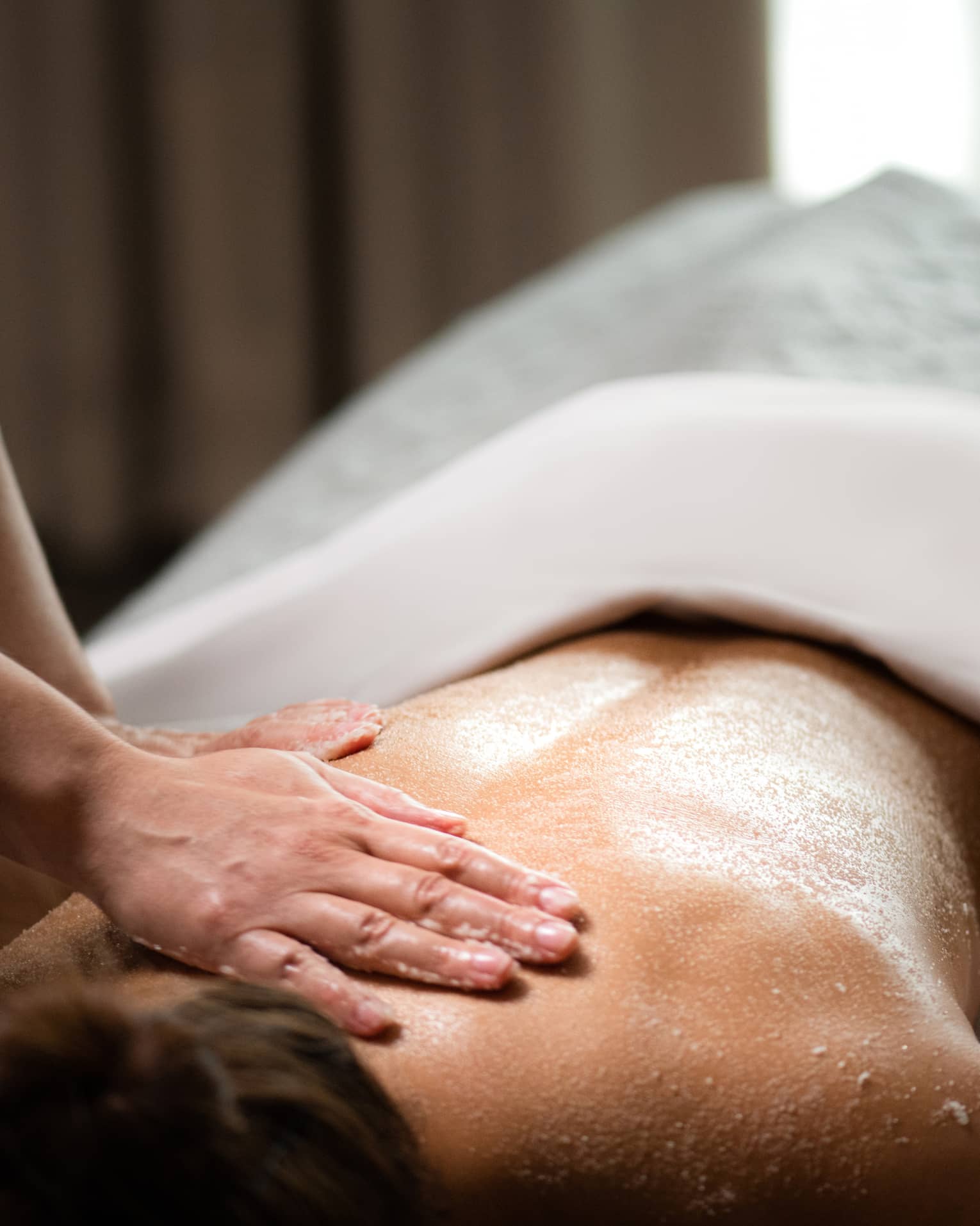 A woman being massaged by a spa staff member while lying down.