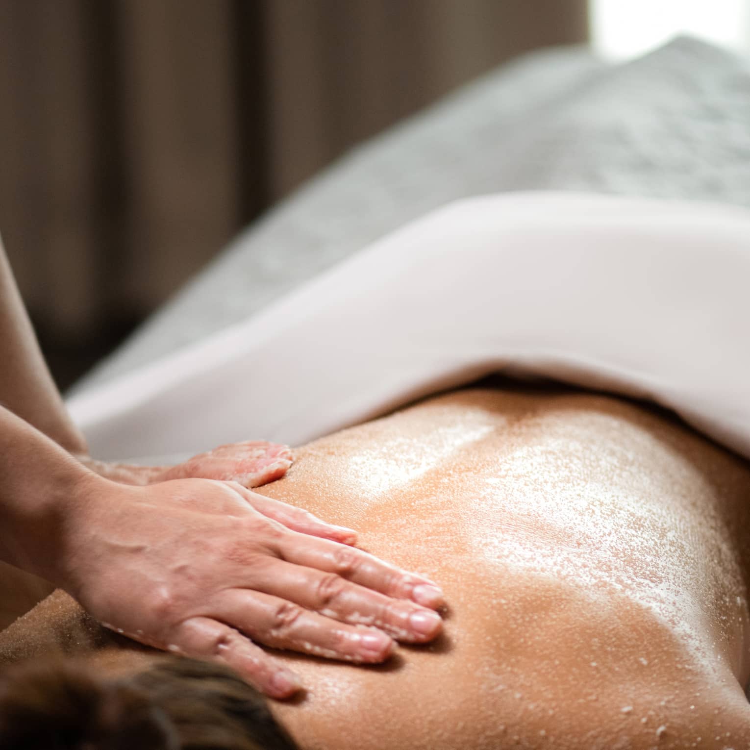 A woman being massaged by a spa staff member while lying down.