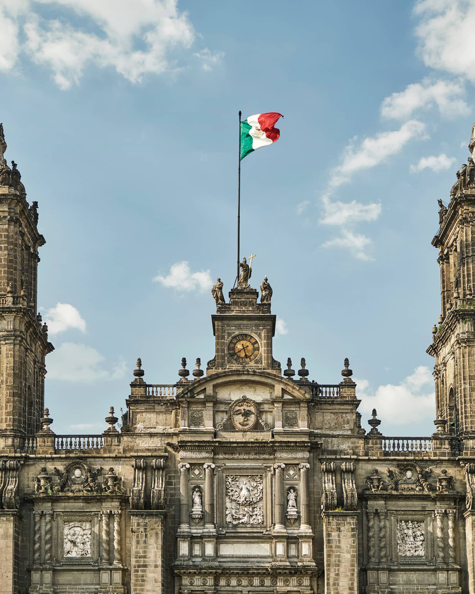 Historic Mexico City building, towers with flag against blue sky