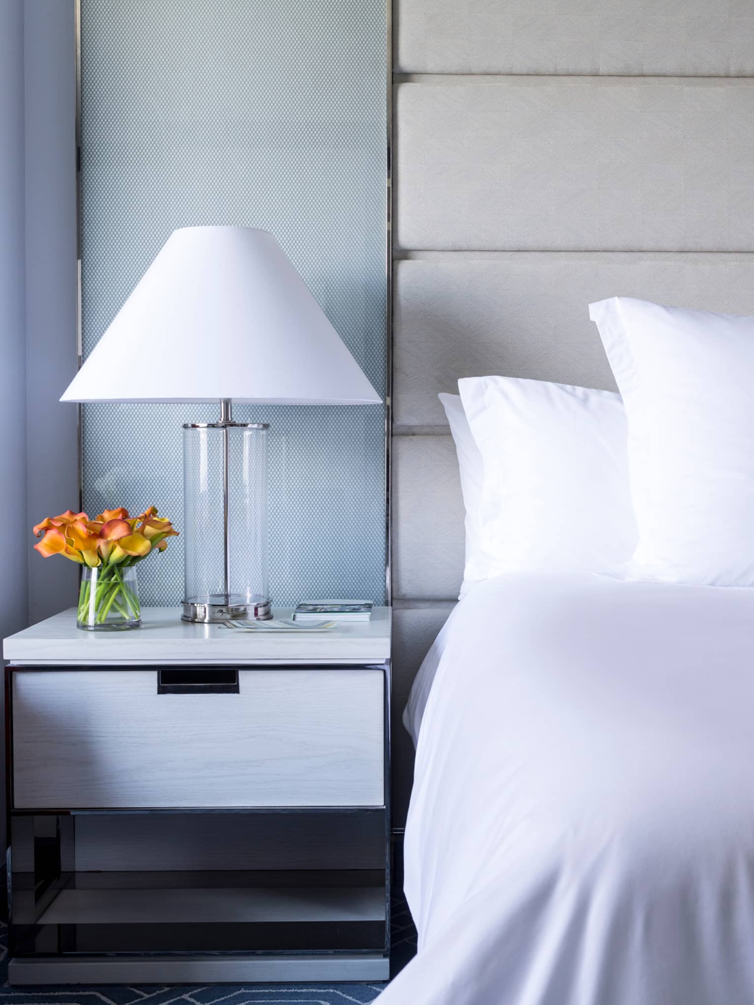 Midtown Deluxe Room close-up of crisp, white bed and linens, lamp next to orange accent chair