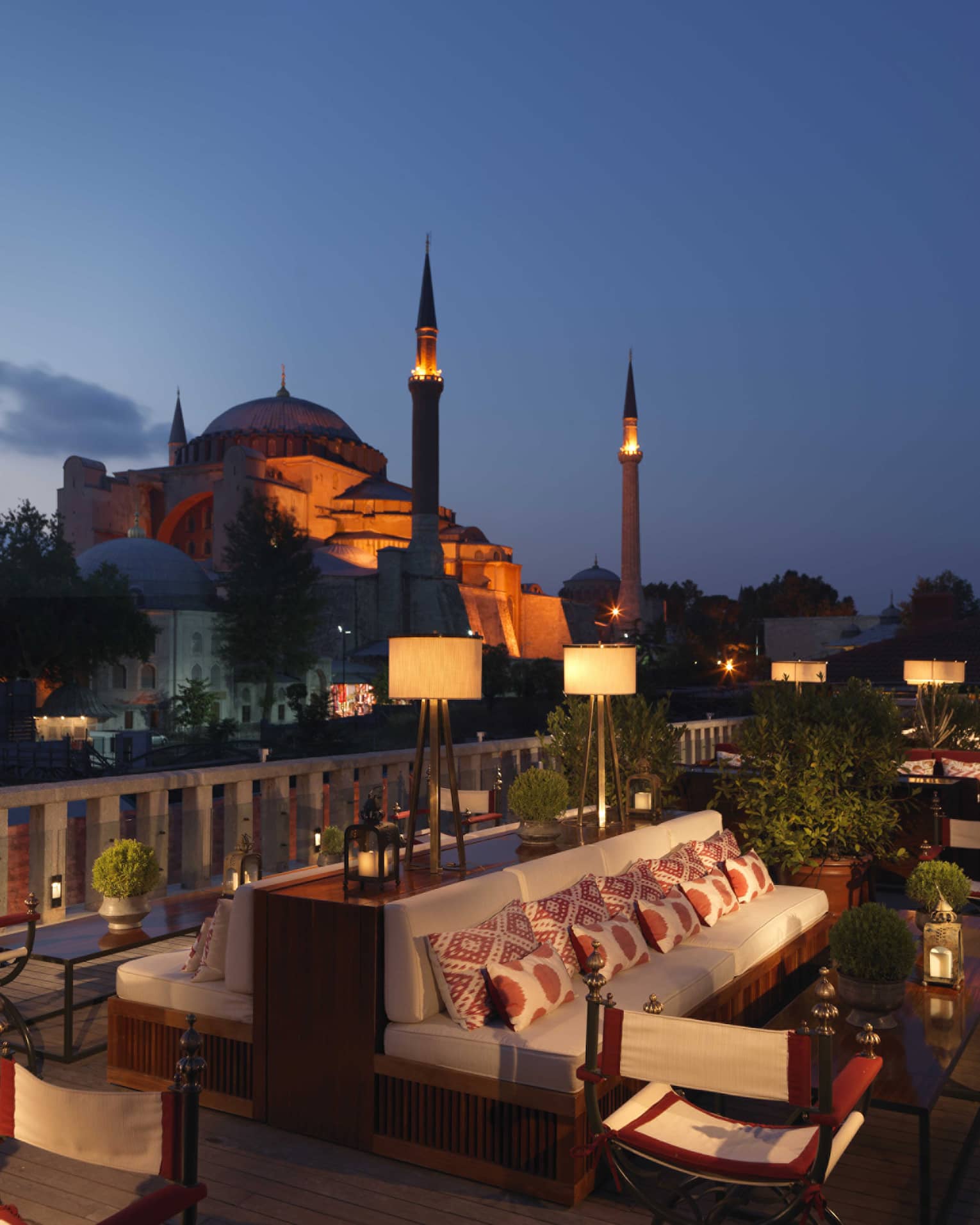 A’YA Rooftop Lounge benches, tables at night with mosque in background