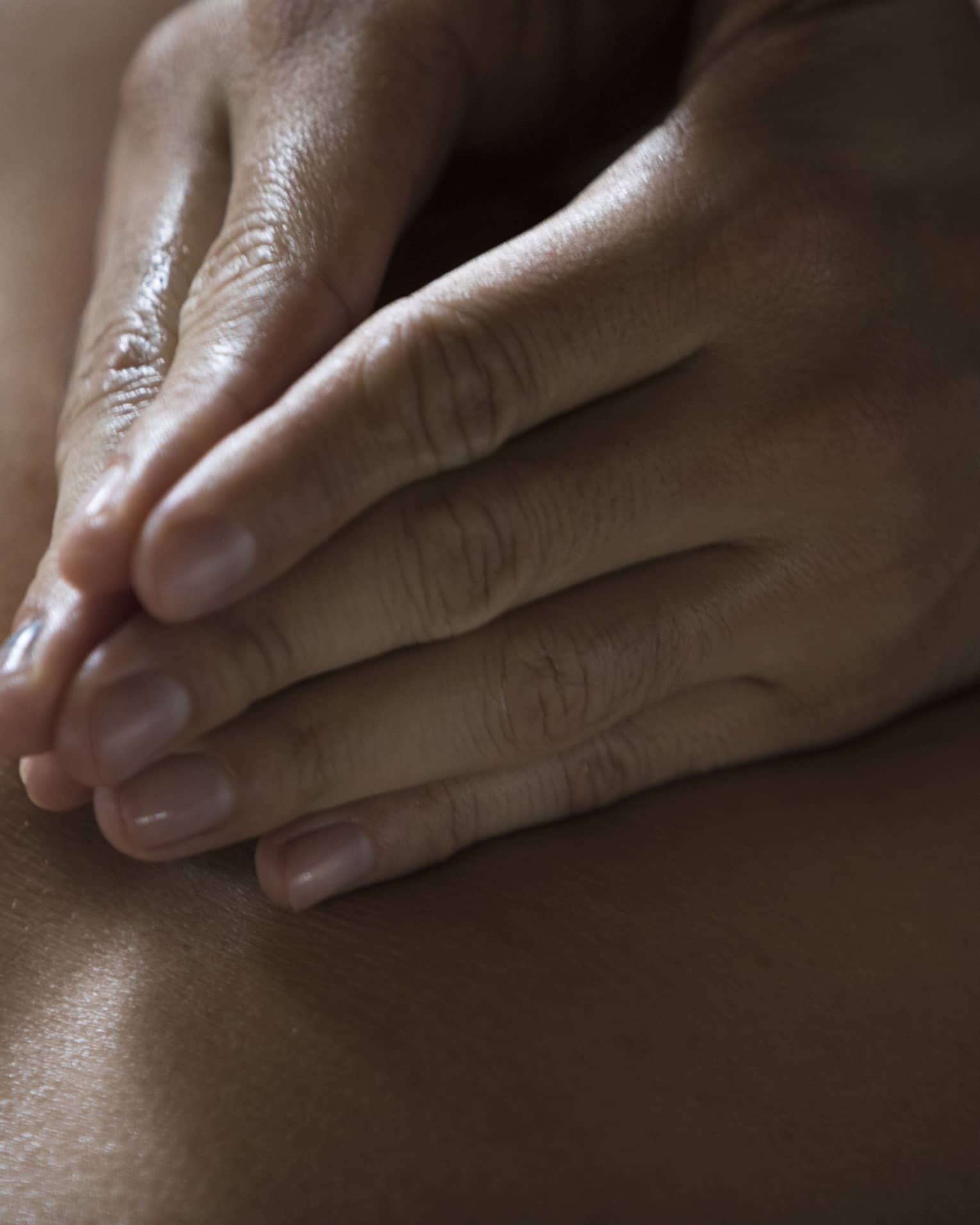 Two hands massage a person's back