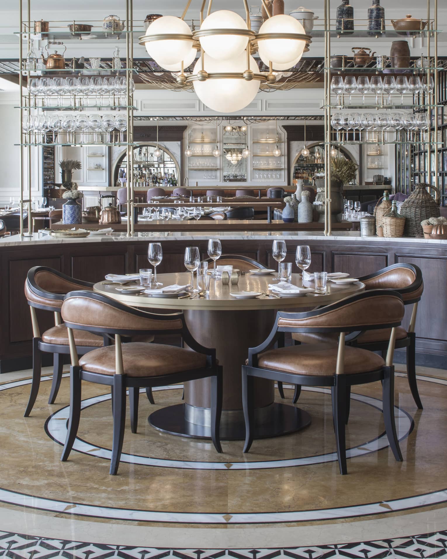 An art-deco restaurant features tables with low-back brown-leather chairs and a counter with copper kettles and wicker jugs.
