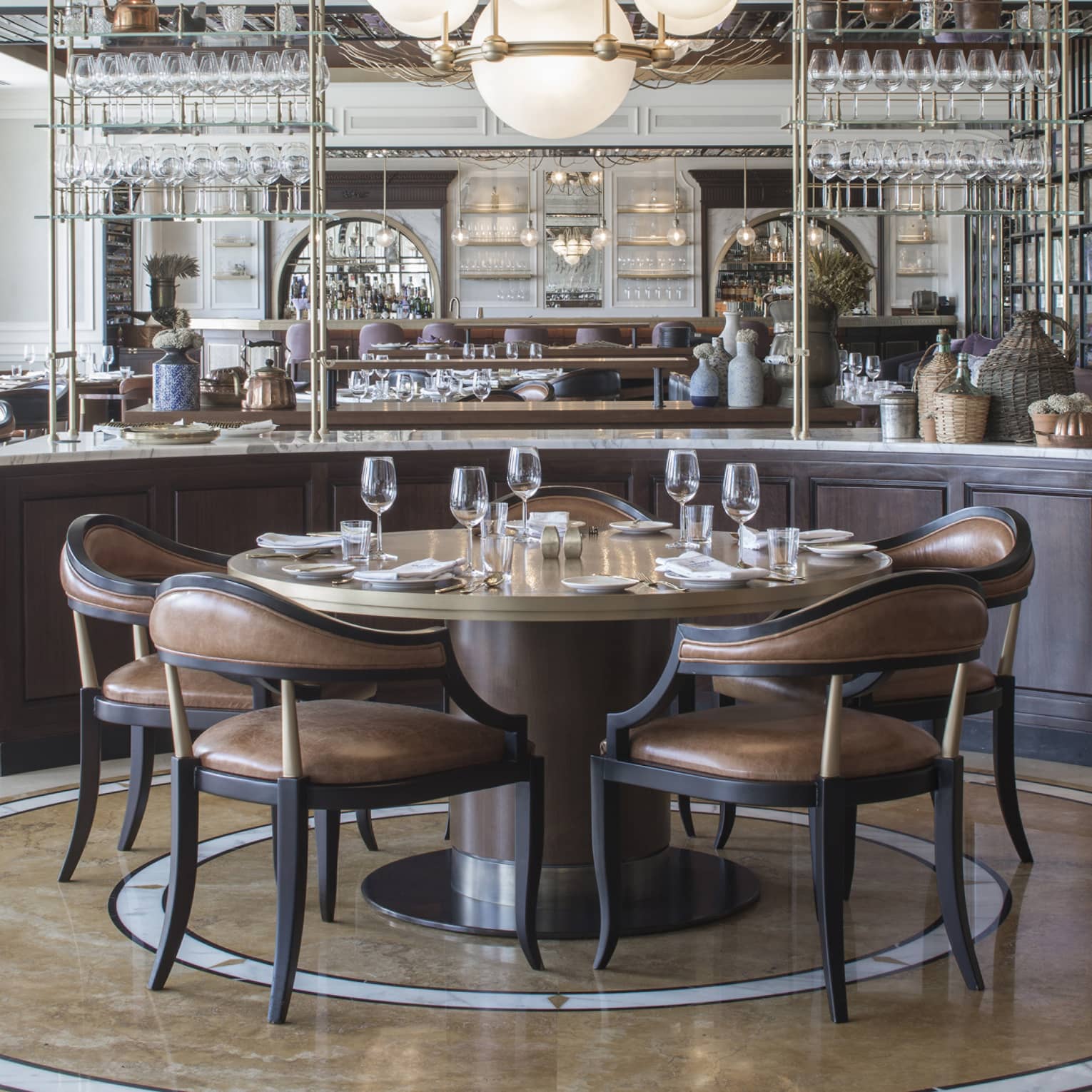 An art-deco restaurant features tables with low-back brown-leather chairs and a counter with copper kettles and wicker jugs.