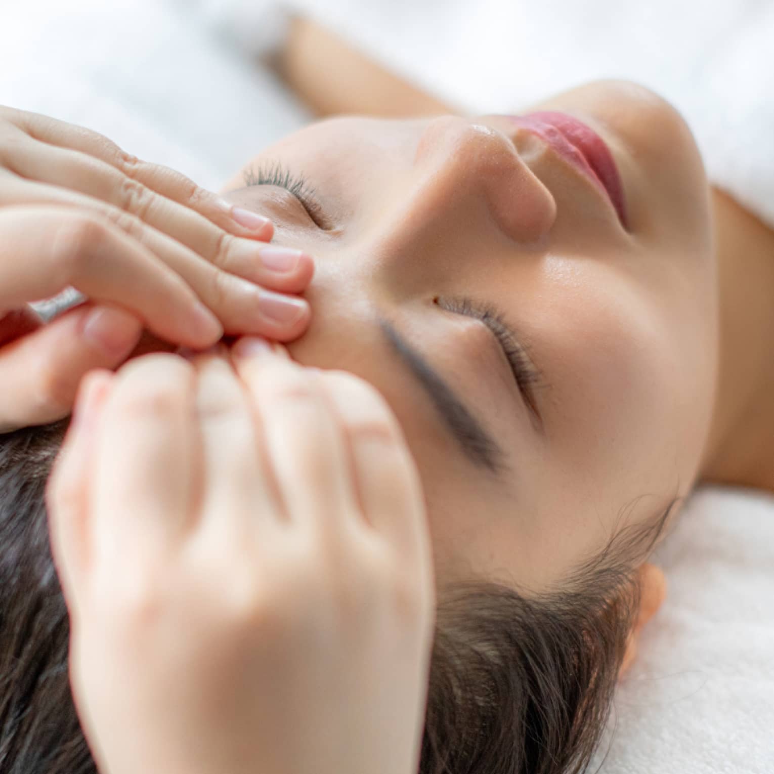 A woman getting a facial massage in a spa.