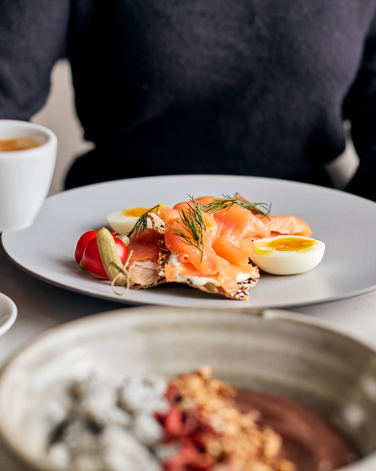 A person drinking coffee while eating a brunch.