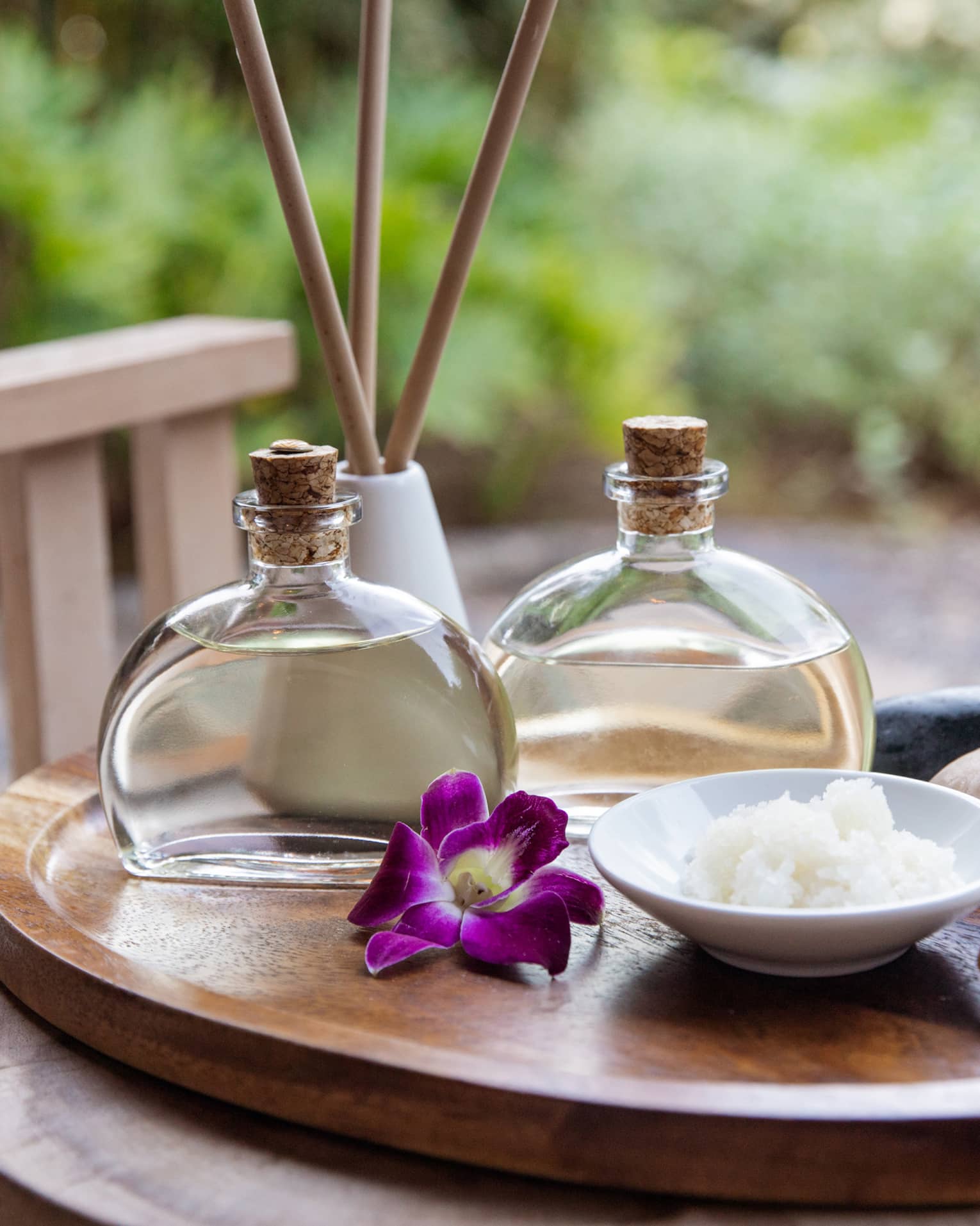 Spa oils and hot stones on wooden platter