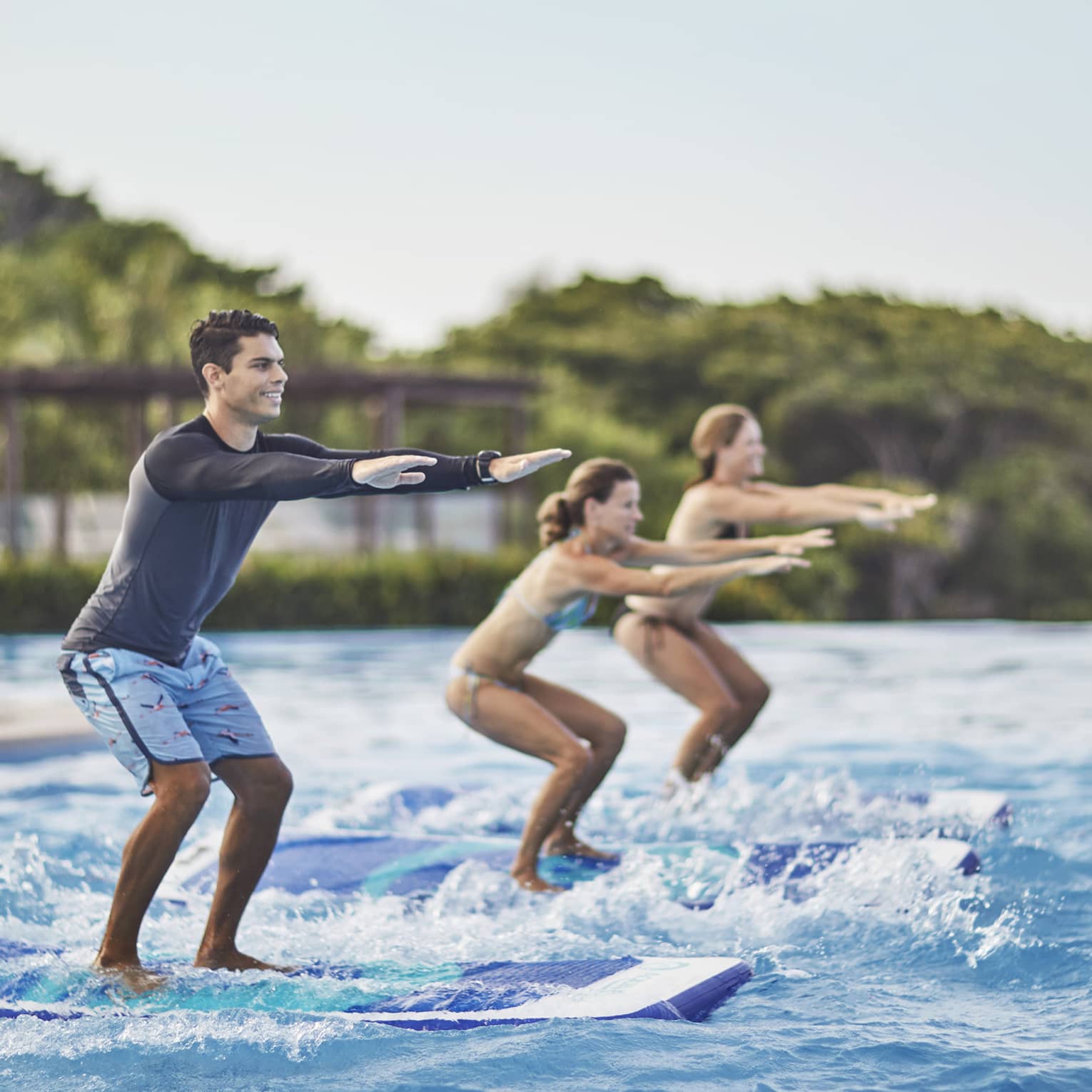 Two guests being instructed how to stand up on surf boards