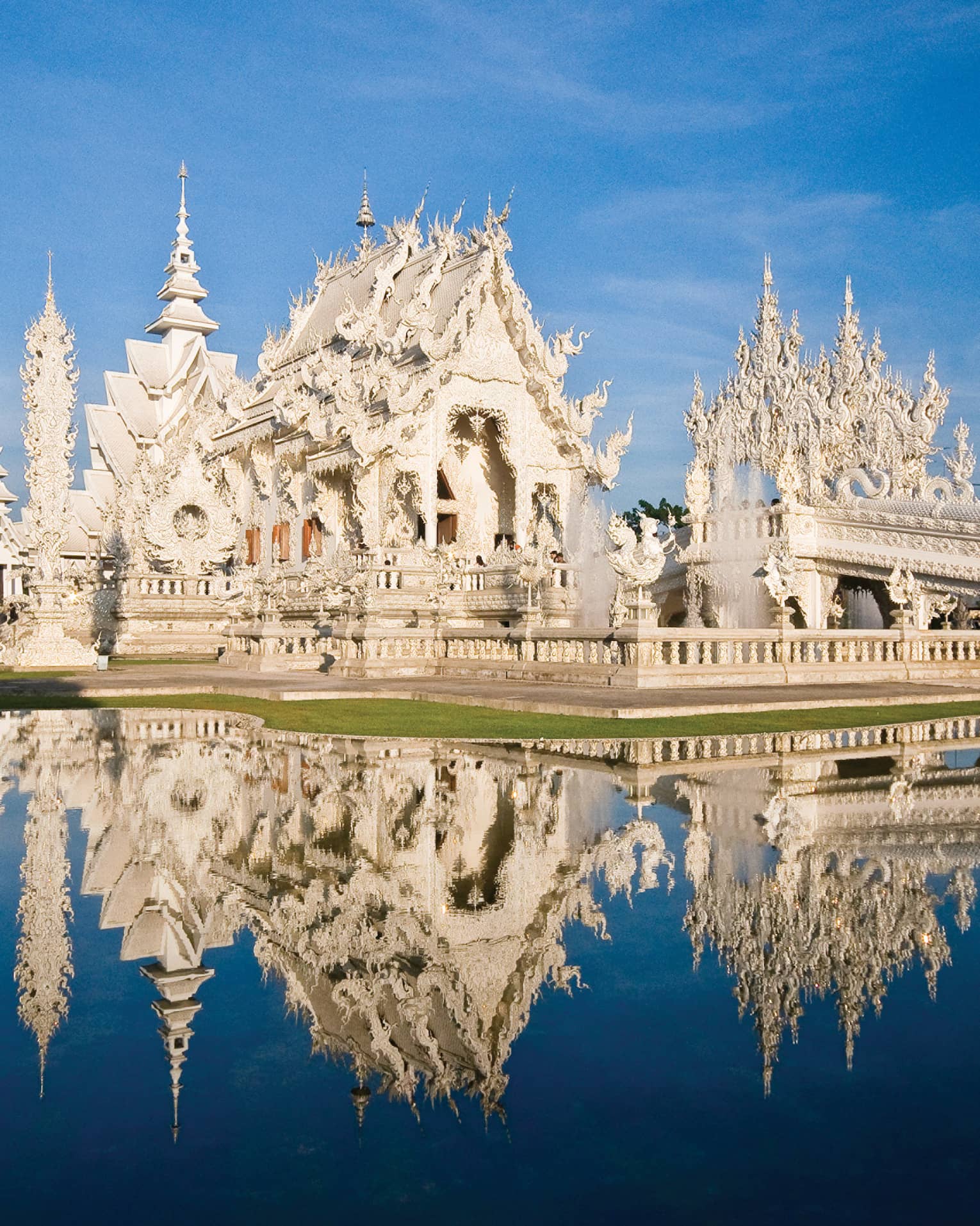 An ornate white castle reflecting in a pond