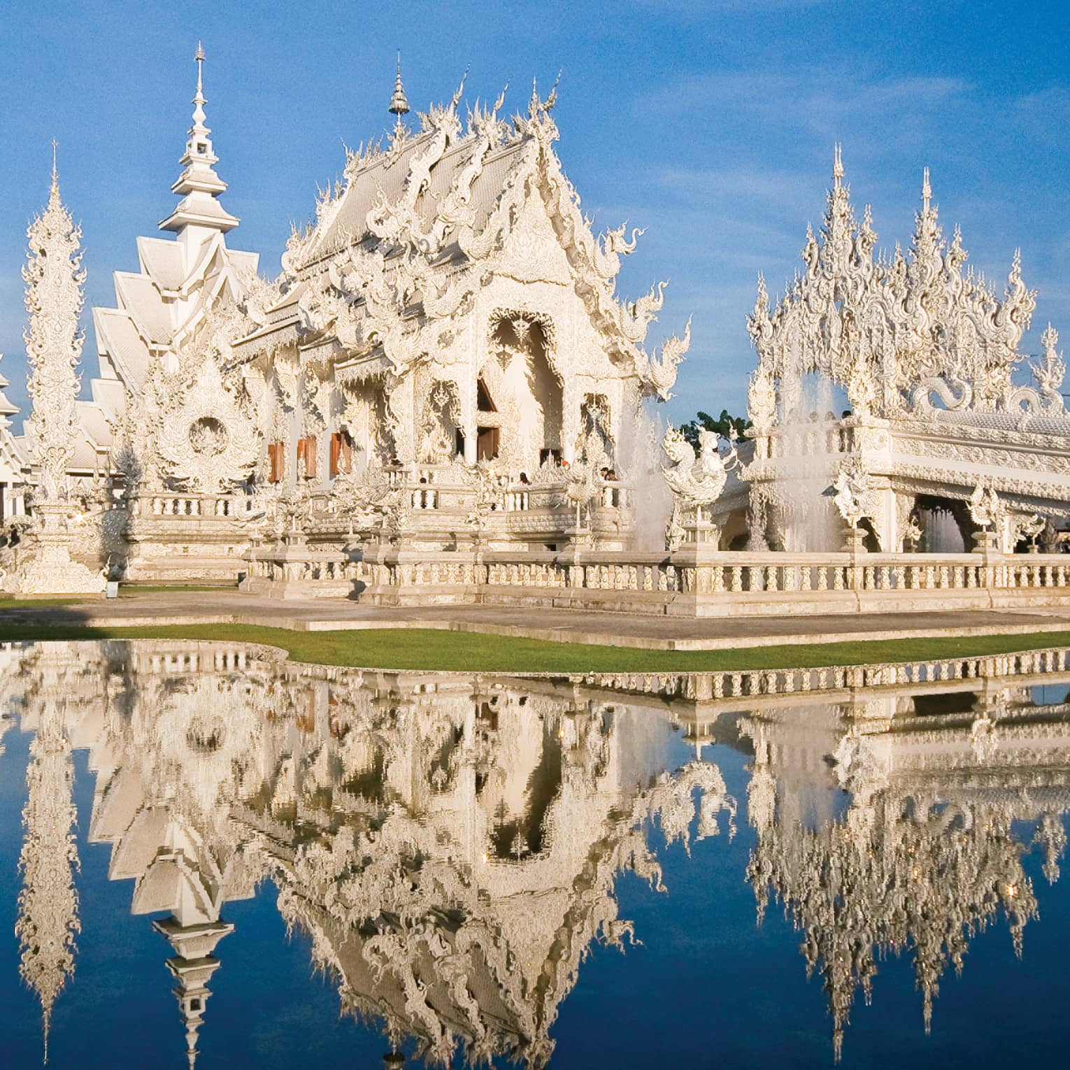 An ornate white castle reflecting in a pond