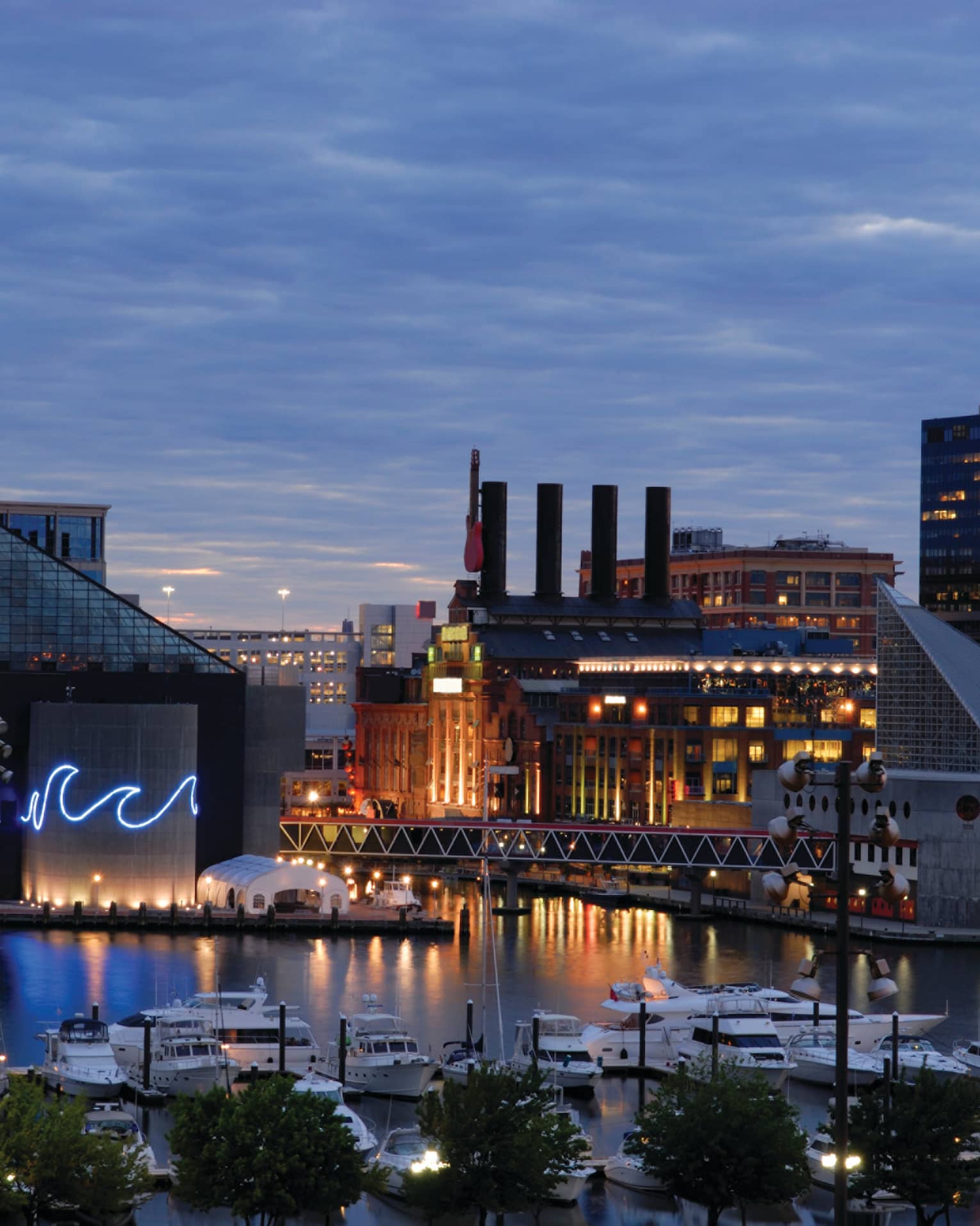 Baltimore buildings with fluorescent wave lights, boats in harbour at dusk