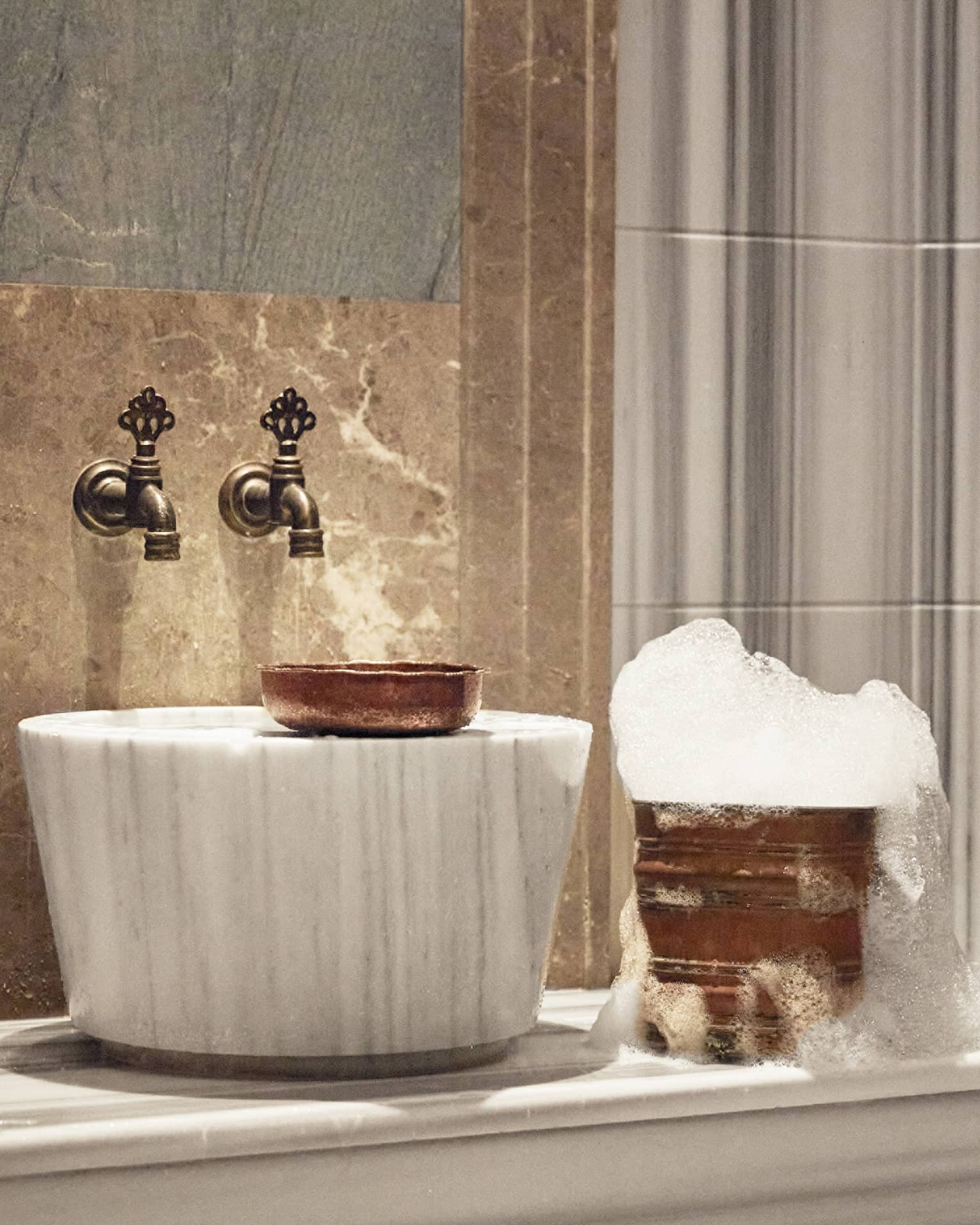 A luxurious sink and golden bucket with bubbles.