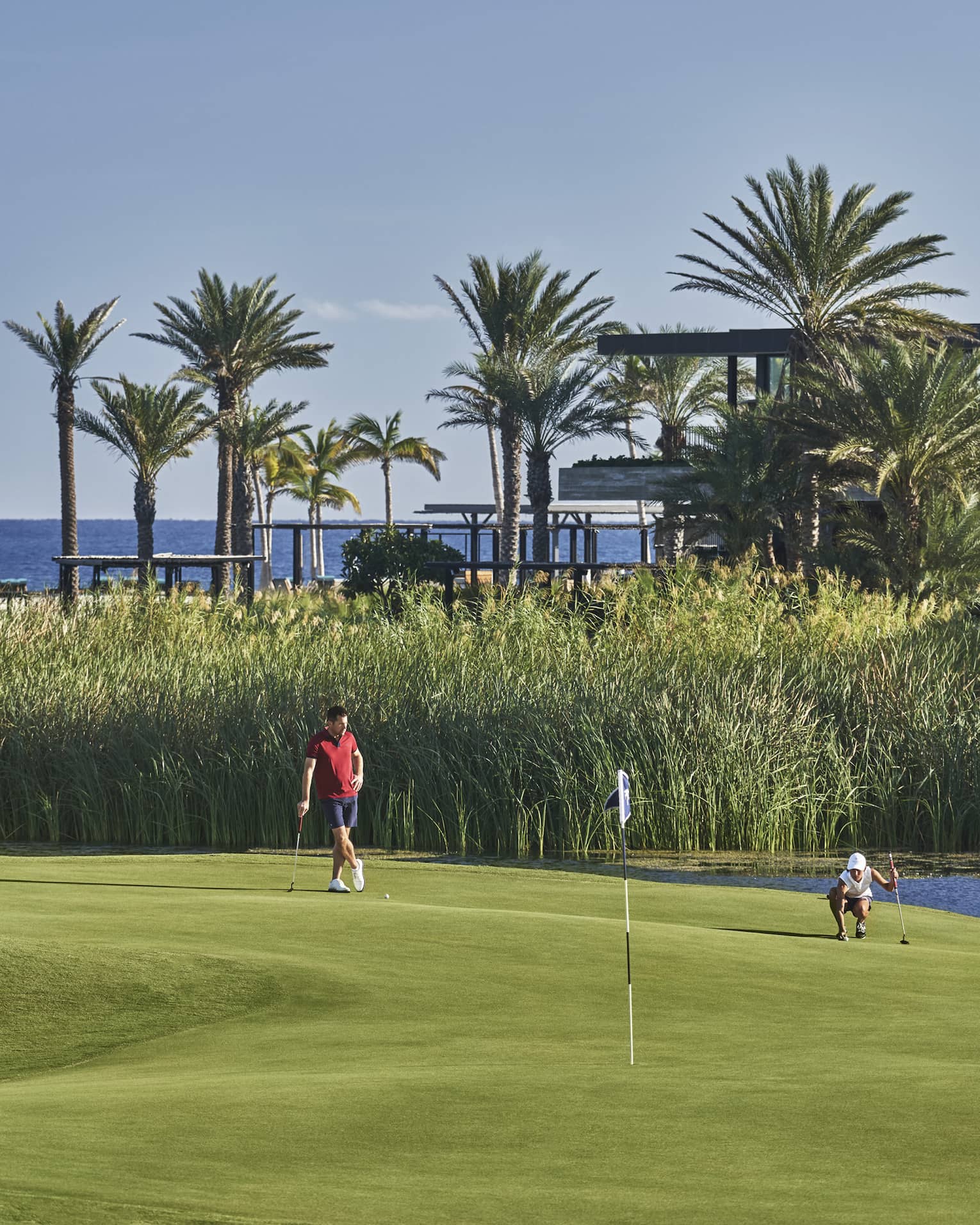 Two golfers enjoy a day on the golf course at four seasons Los Cabos with palm trees and the ocean in the background