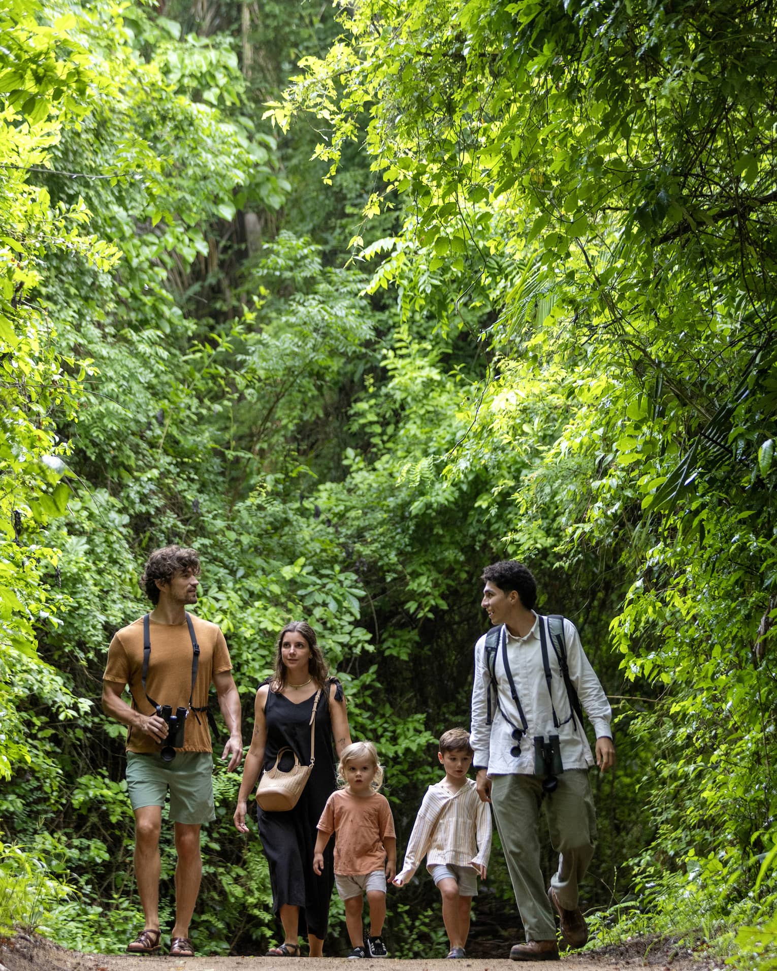 Three adults and two children walk in the forest