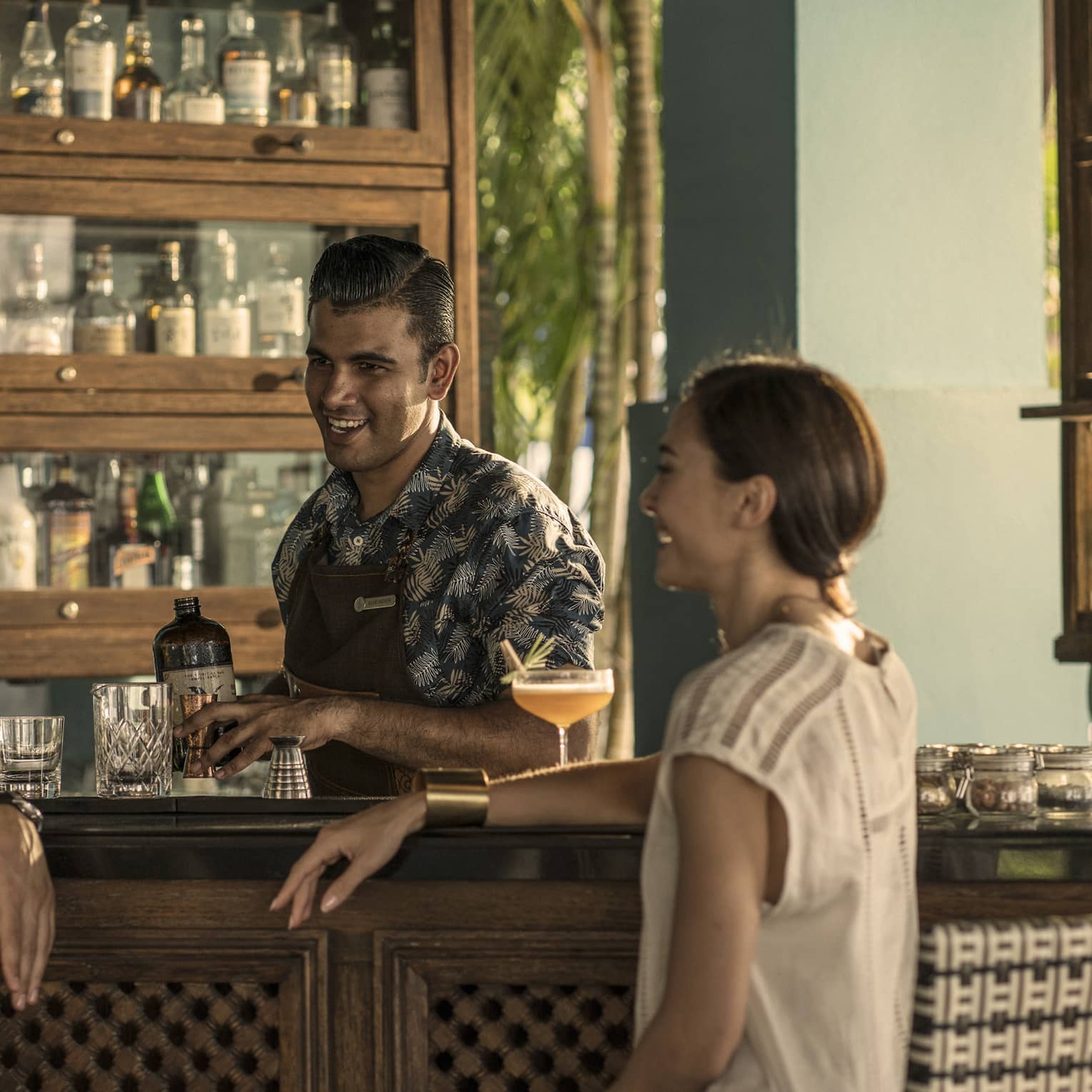 Two guests chat with a bartender at rhu bar while he makes a drink