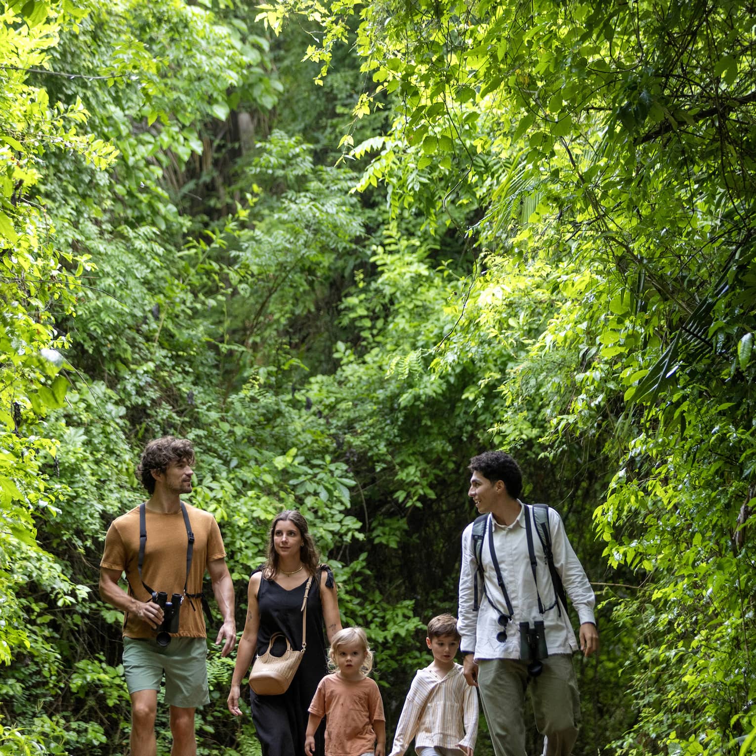 Three adults and two children walk in the forest
