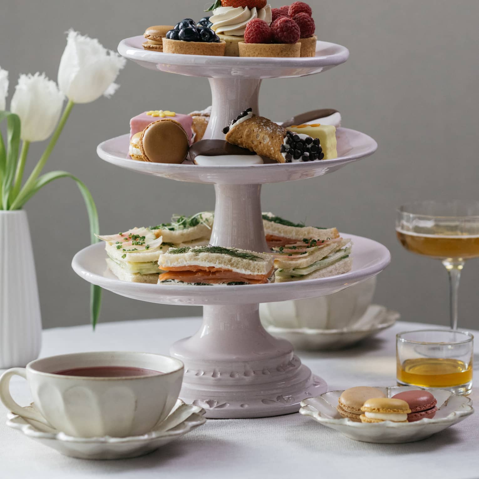 Afternoon tea setting, three-tiered dessert tray, tulips in vase, martinis and tea cups