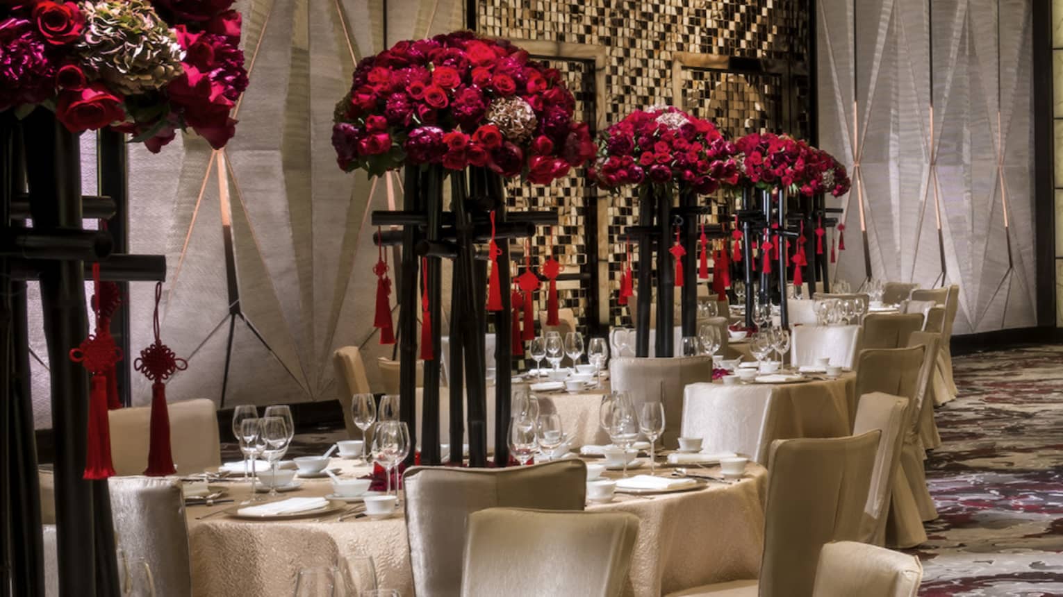Grand Ballroom banquet tables and chairs with silk linens, red flowers in tall vases 