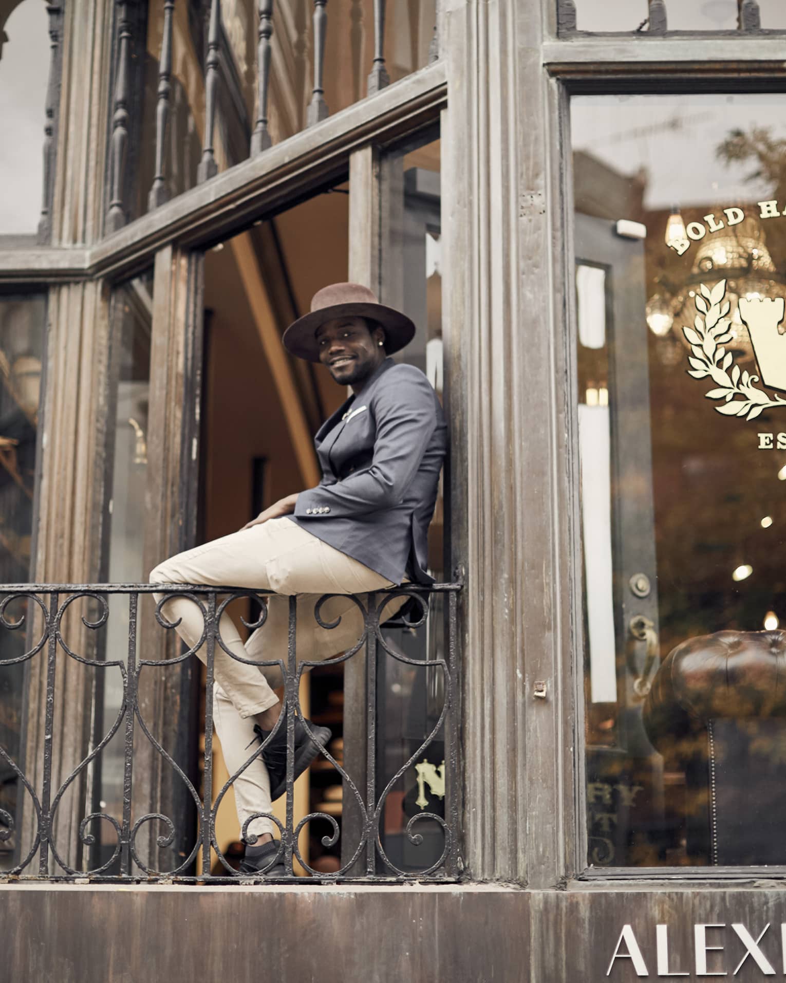 A well dressed man leaning on a wall outside of a store.