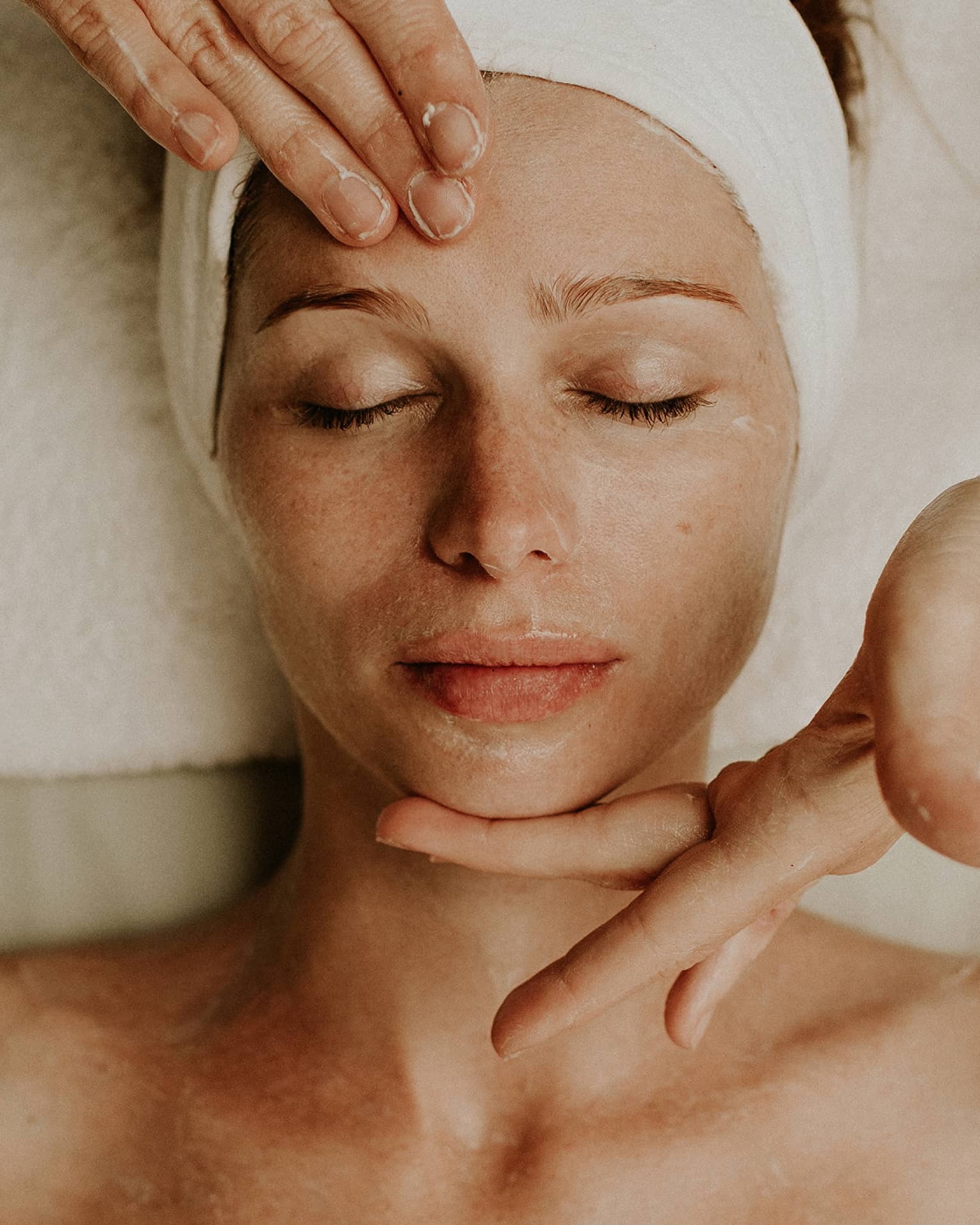 A woman reclines as a spa attendant performs a facial