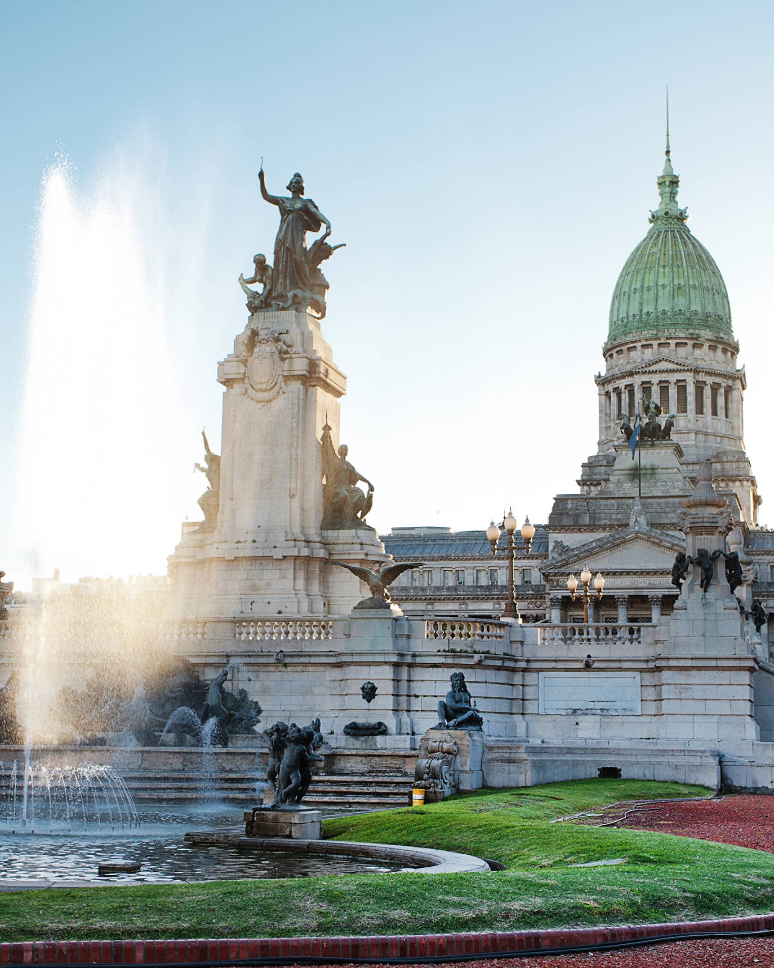 Large fountain, historic building and courtyard on sunny day