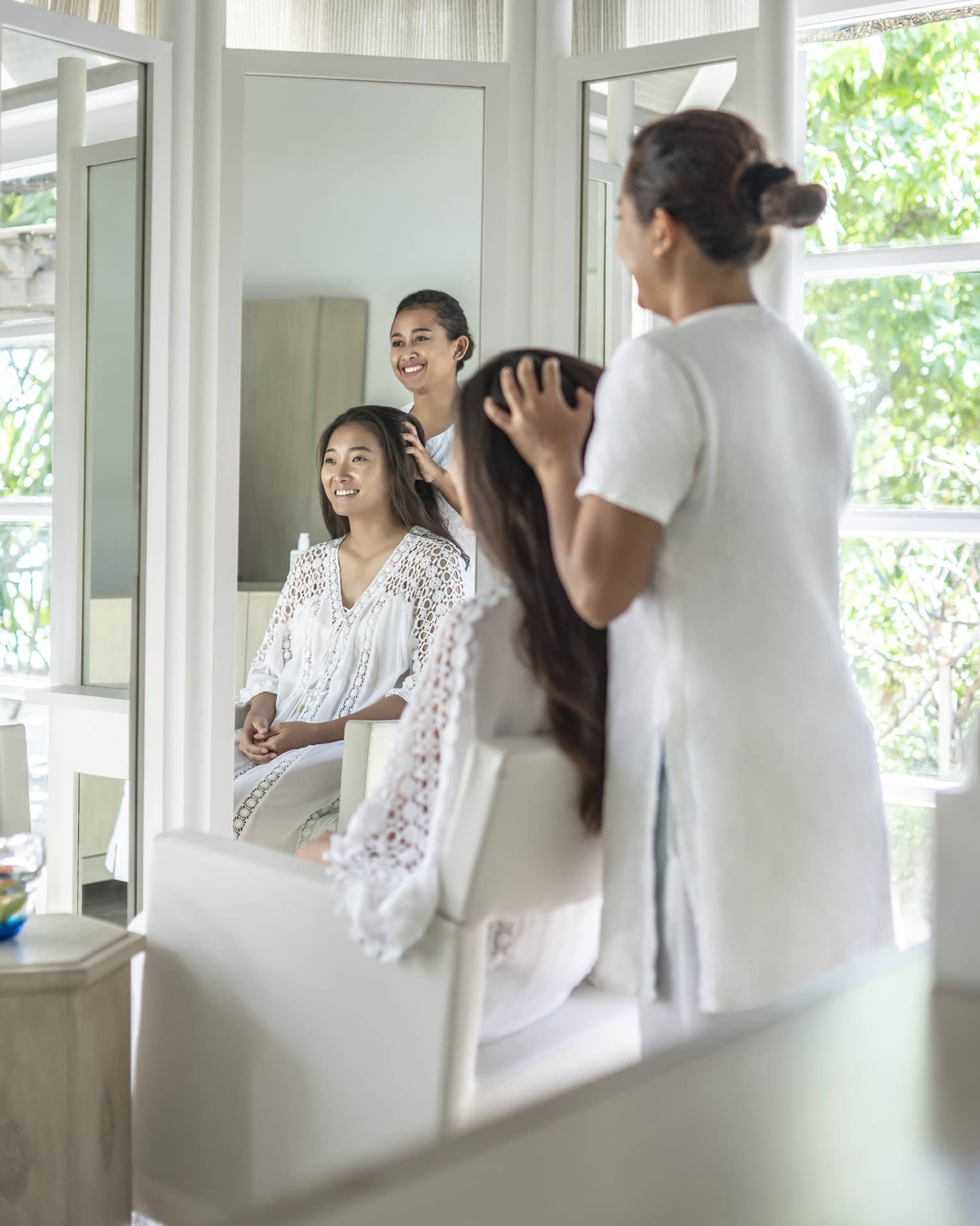 Person enjoying a hair treatment in a spa salon with large windows, surrounded by lush greenery