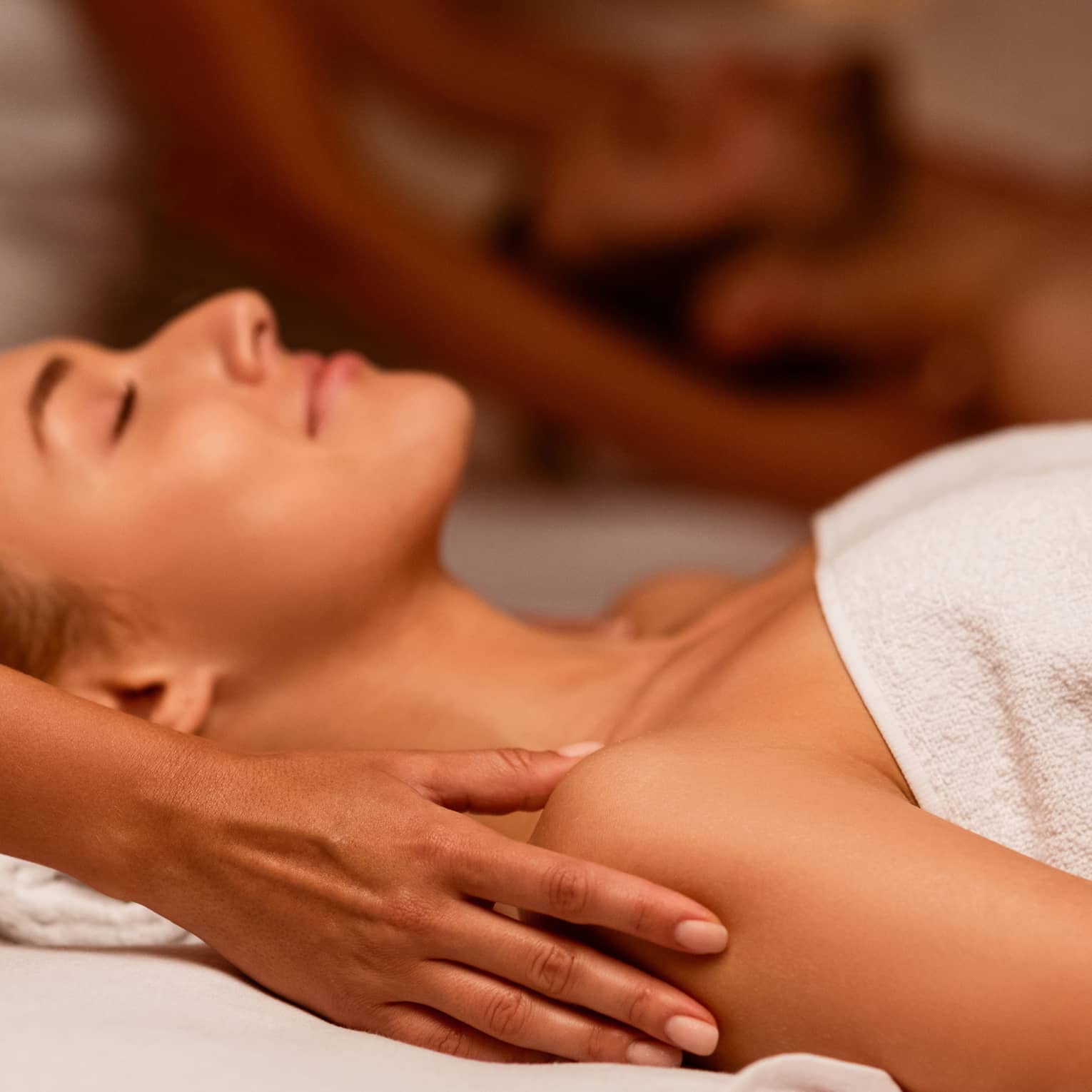 Two spa therapists perform a couples' massage