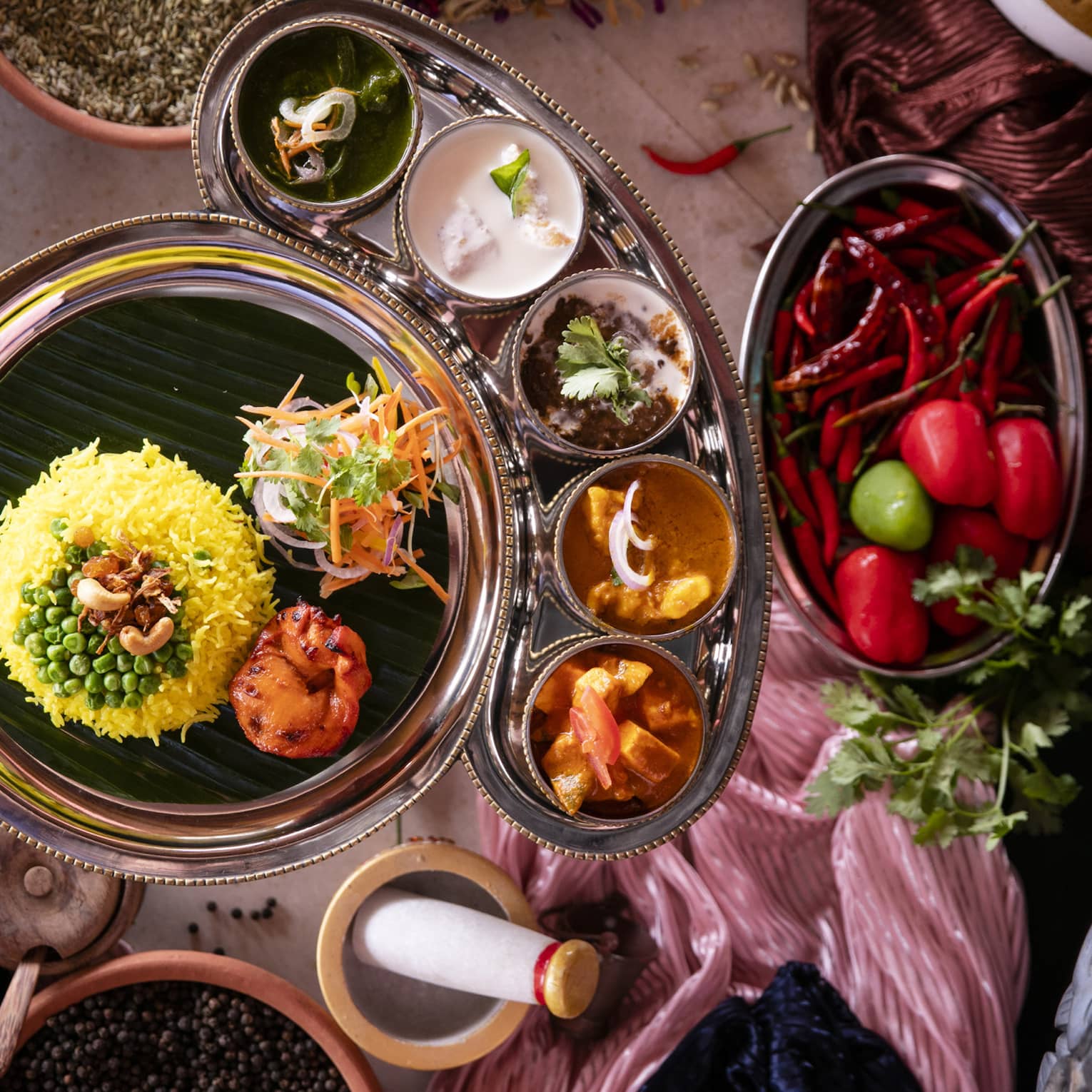 Aerial view of curry dish with rice, bowls of condiments and mortar and pestle