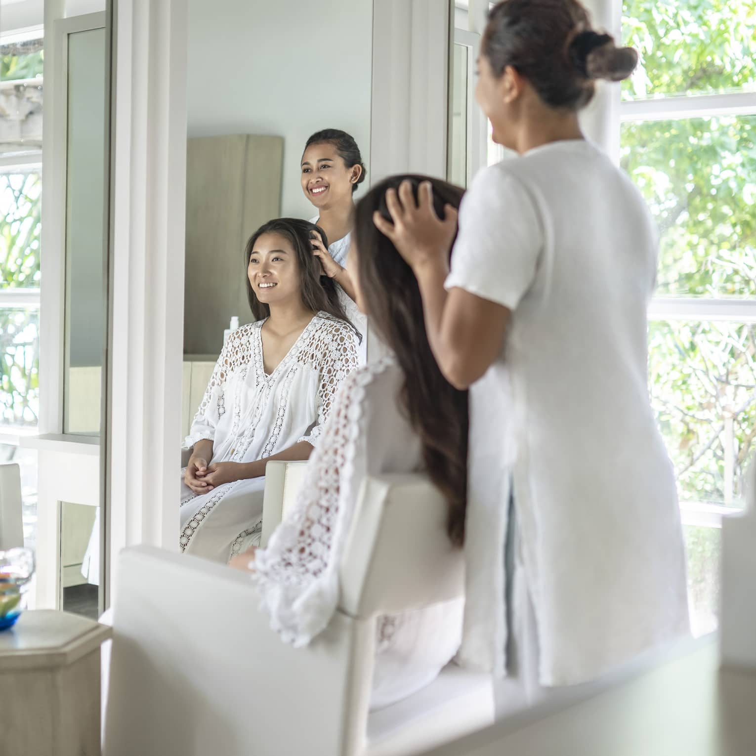 Person enjoying a hair treatment in a spa salon with large windows, surrounded by lush greenery