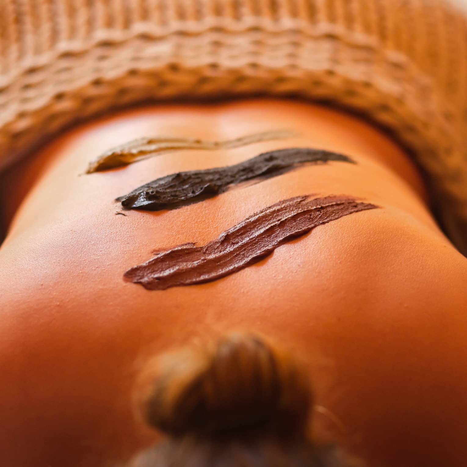 Three different-coloured smears of mud on woman?s bare back during massage