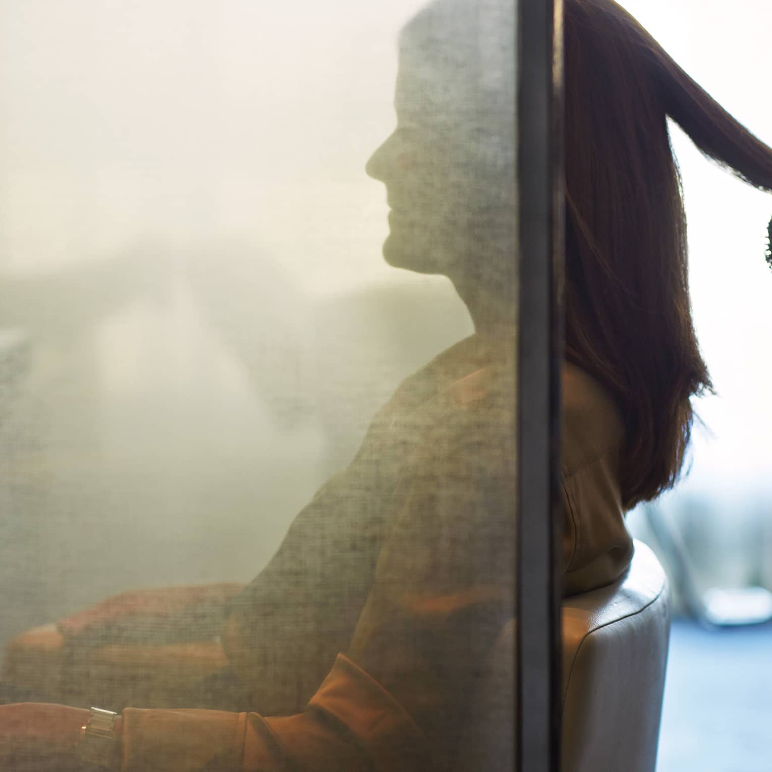 Silhouette of woman behind salon screen as hairdressers brushes, blow dries hair