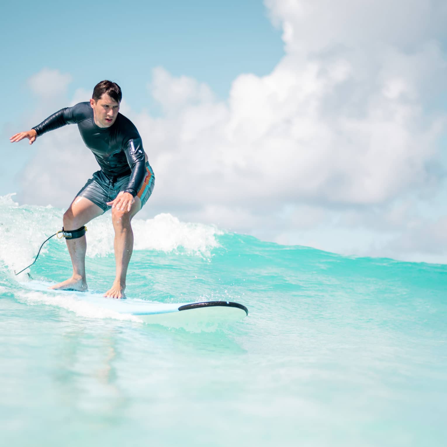 Man balances on surf board over wave