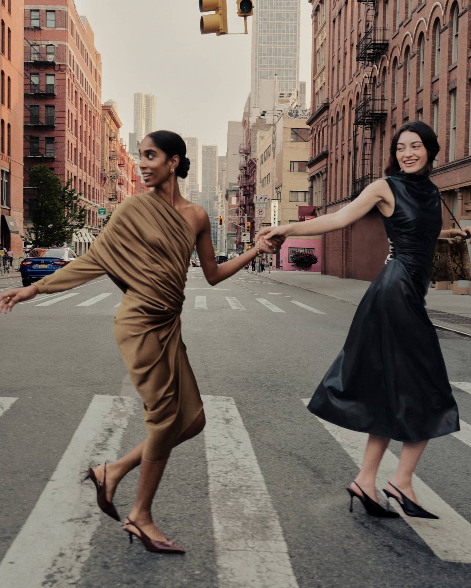Two women holding hands cross a street in New York City.