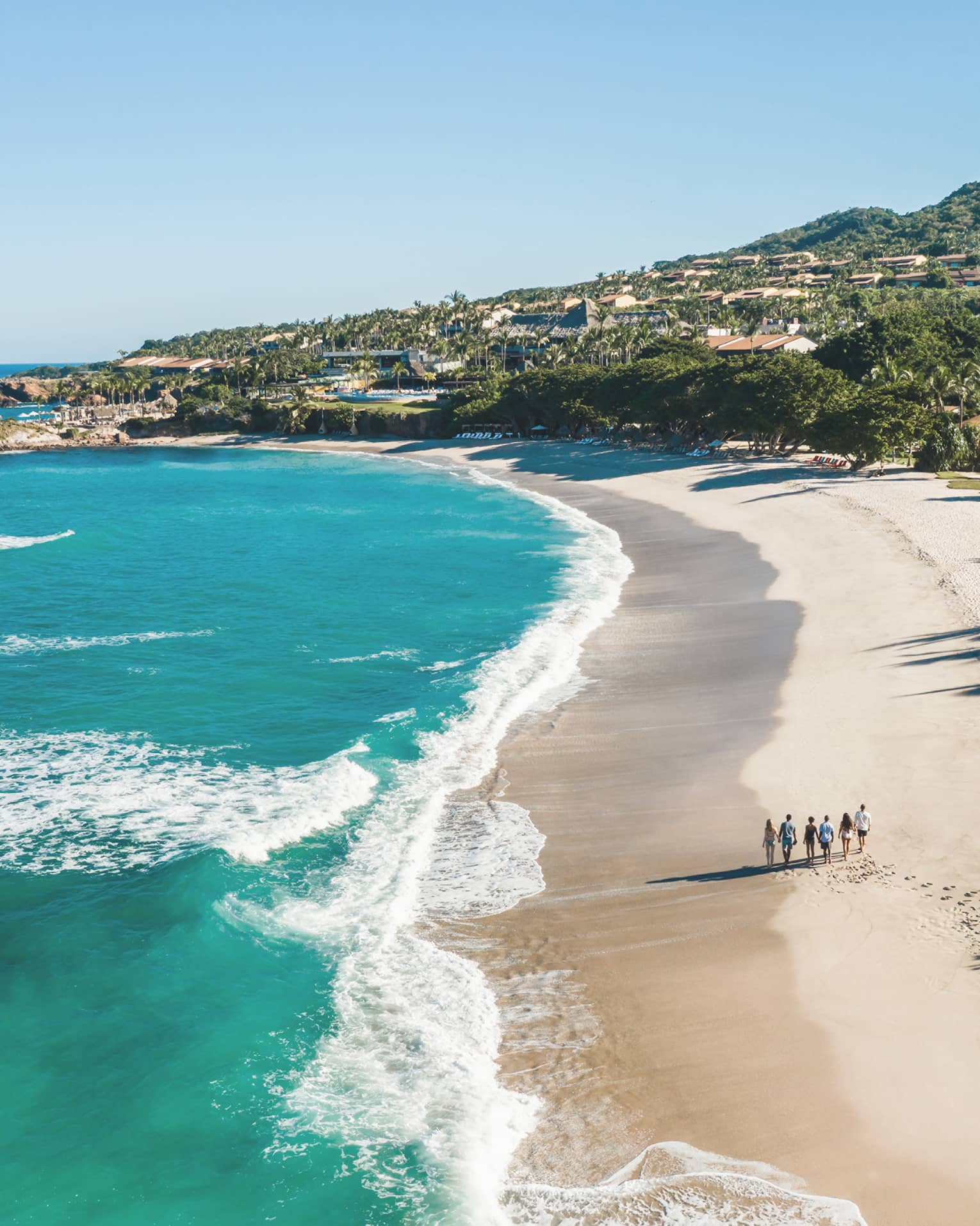 A group of guests strolling on a pristine private beach