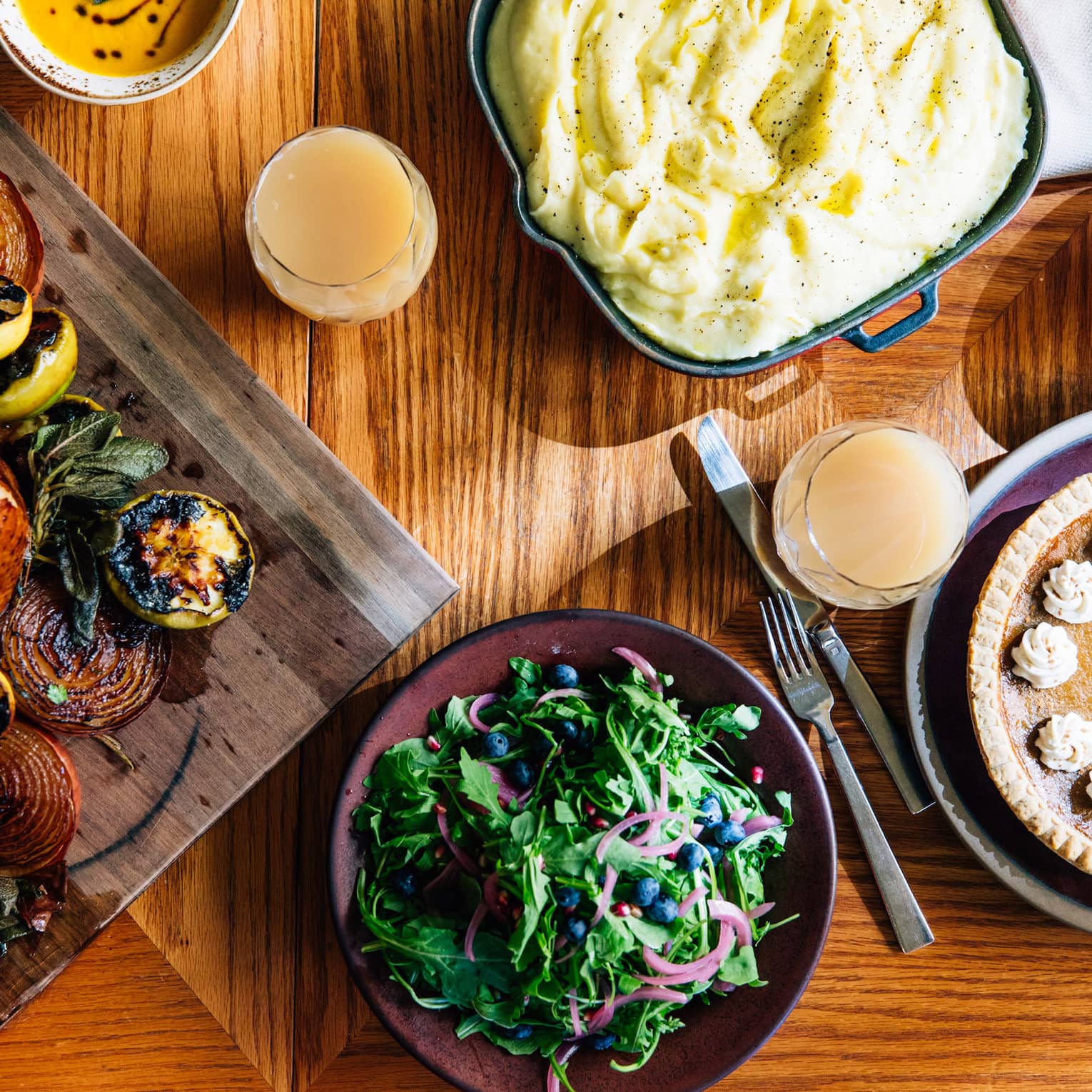 An aerial shot of a thanksgiving dinner including a roasted turkey with vegetables, mashed potatoes, salad and pumpkin pie