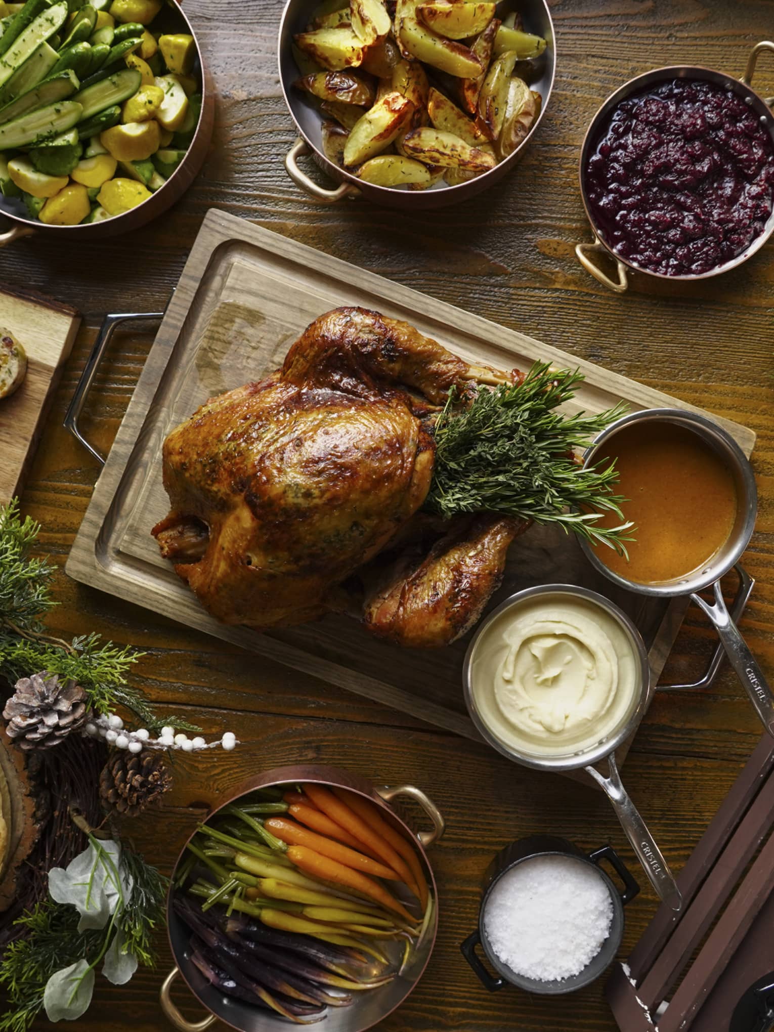 A full festive feast with a Turkey in the centre, and several copper pots of stewed vegetables surrounding