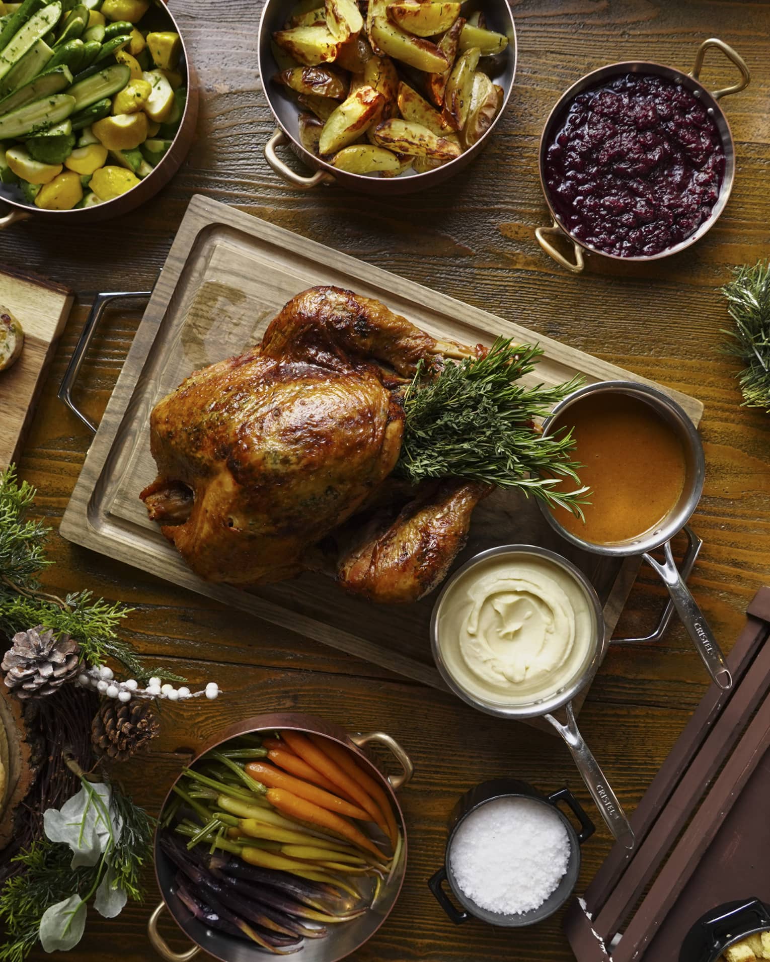 A full festive feast with a Turkey in the centre, and several copper pots of stewed vegetables surrounding