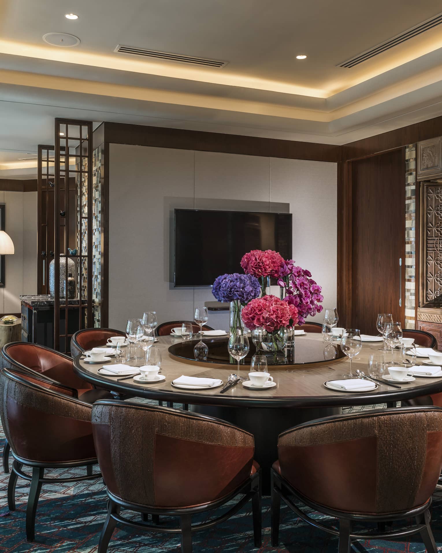 Leather bucket chairs around private meeting dining table, TV on wall