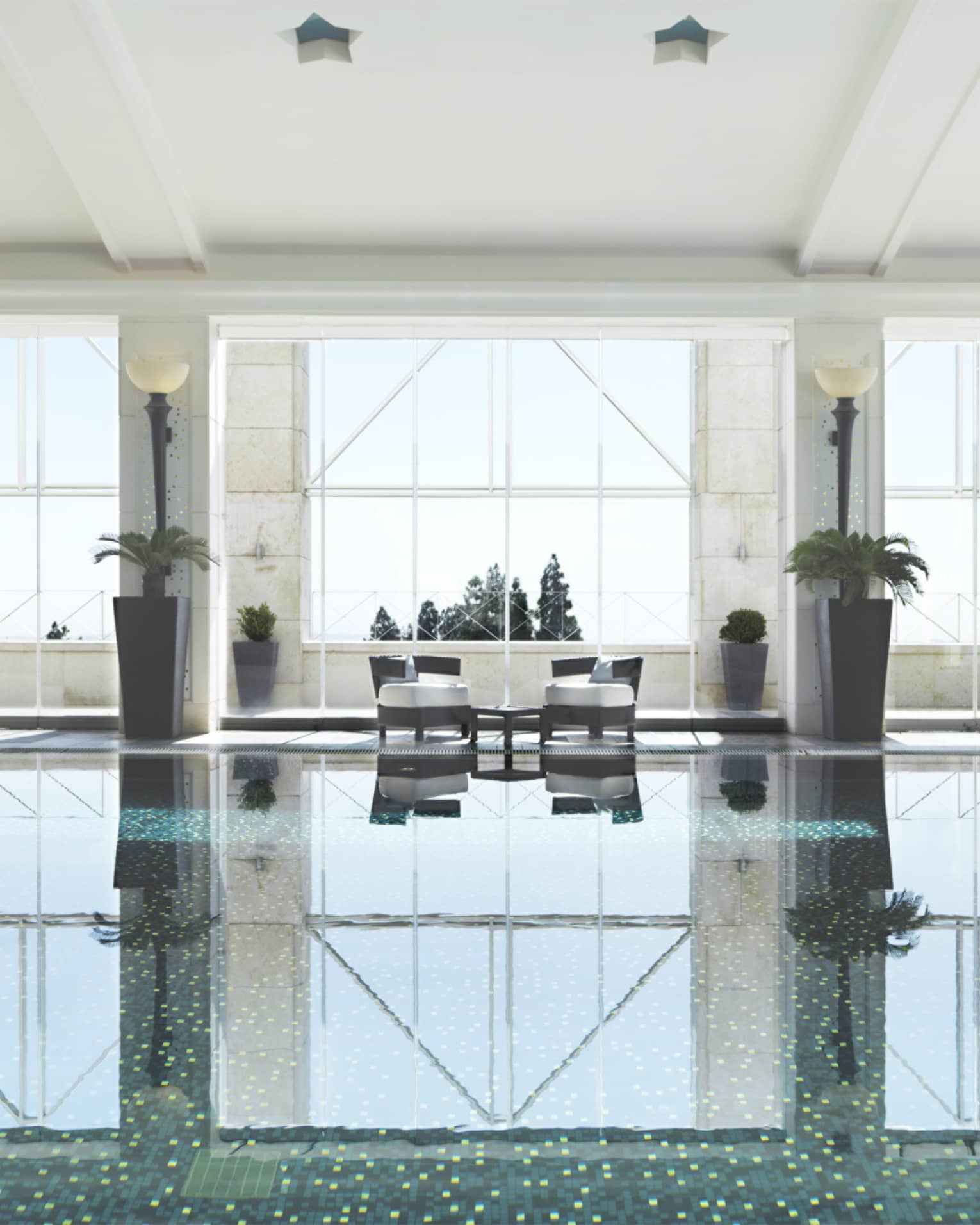 Indoor swimming pool reflecting light of three tall windows, white walls and pool chairs
