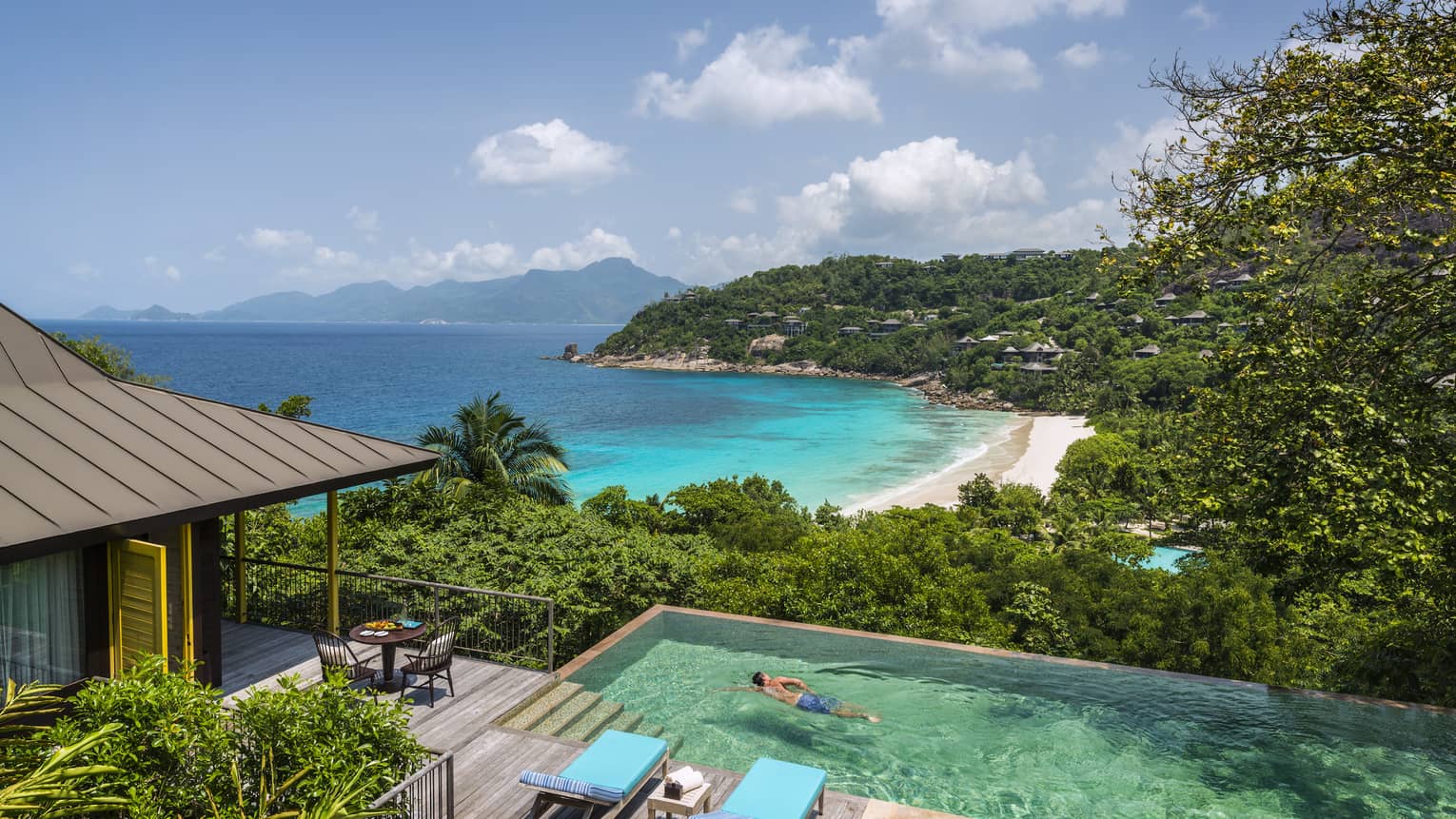 Two-bedroom Ocean View Suite deck, man swims laps in plunge pool, ocean and beach seen below