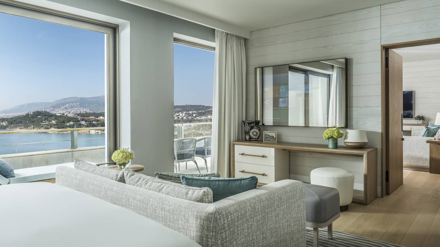 Arion One Bedroom Suite with bed, grey patterned loveseat, doorway to living area, ocean views
